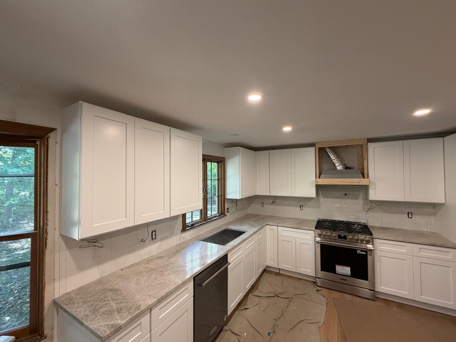 White kitchen with cabinets, countertops, and appliances, under construction.