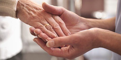A nurse holding a residents hand