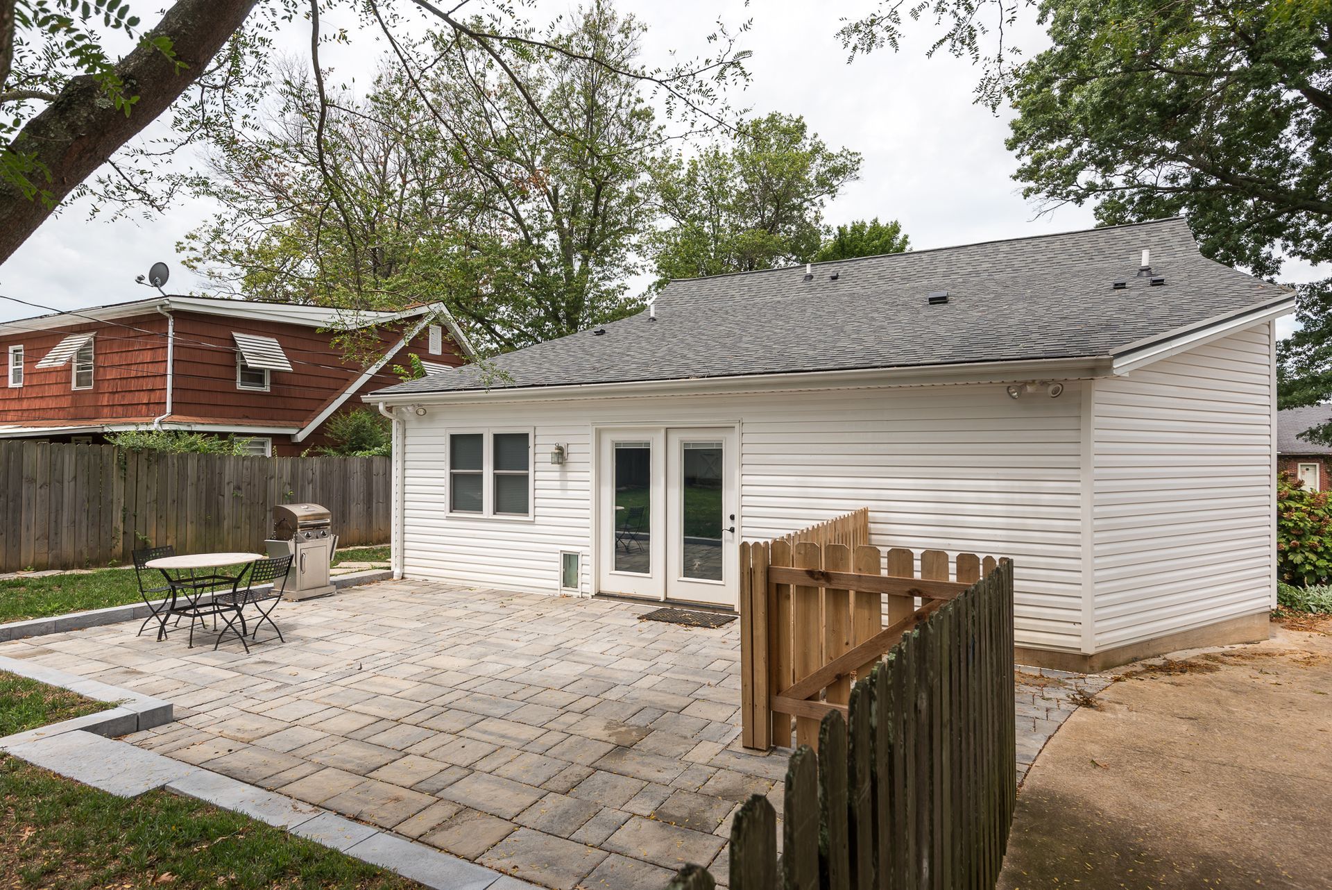 A small white house with a patio and a wooden fence