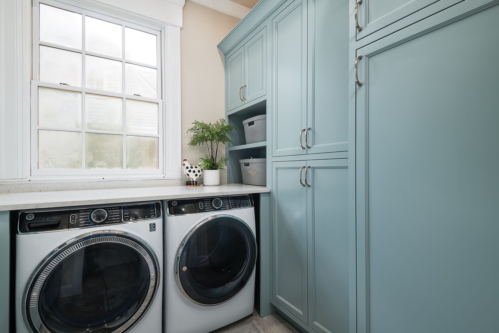 A laundry room with a washer and dryer and blue cabinets.