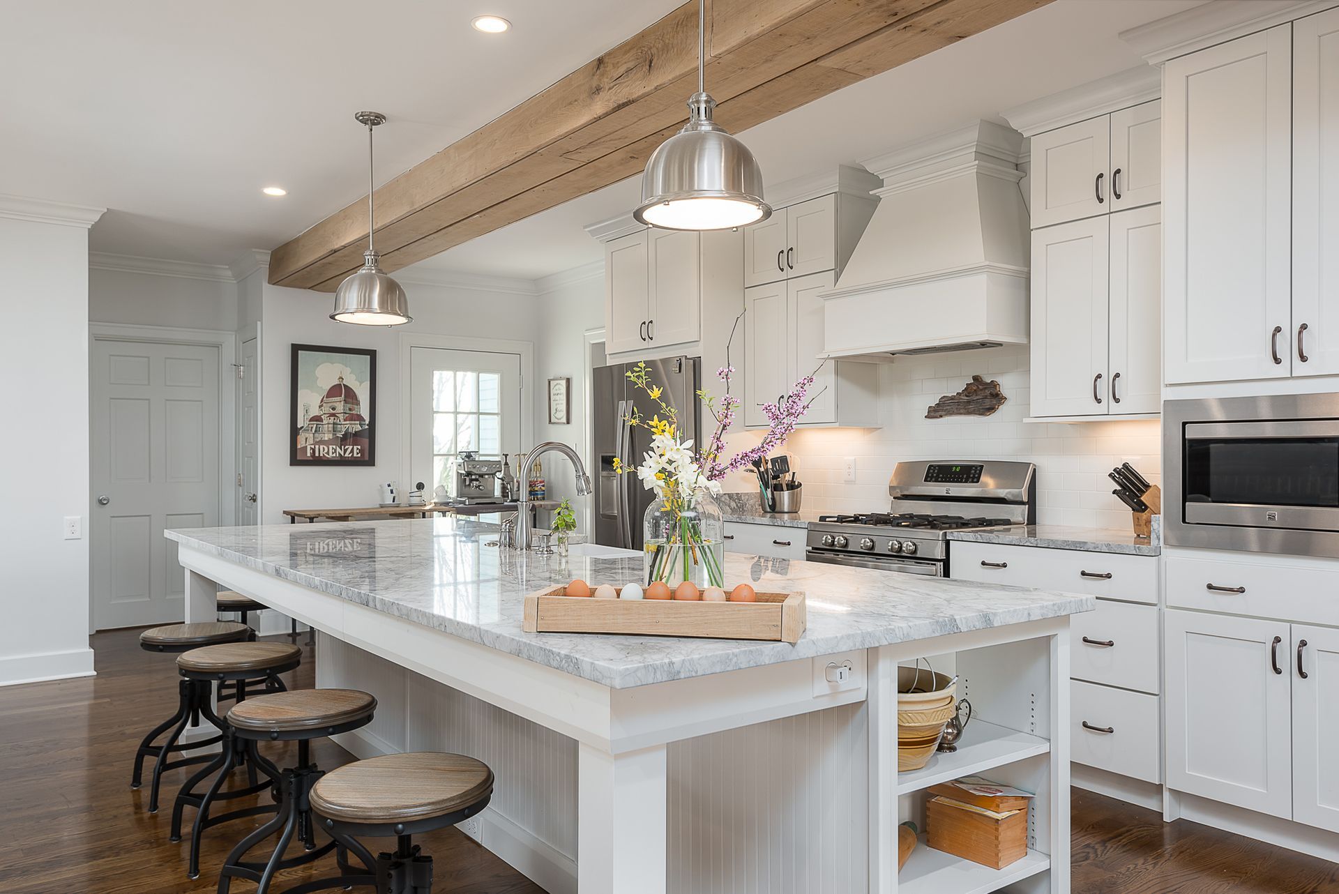 A kitchen with white cabinets , granite counter tops , stainless steel appliances and a large island.