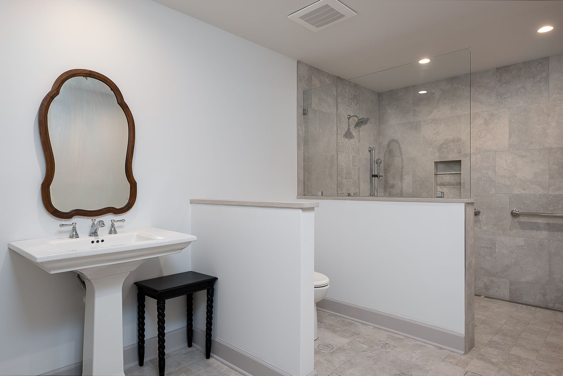 A bathroom with a sink , mirror , toilet and walk in shower.