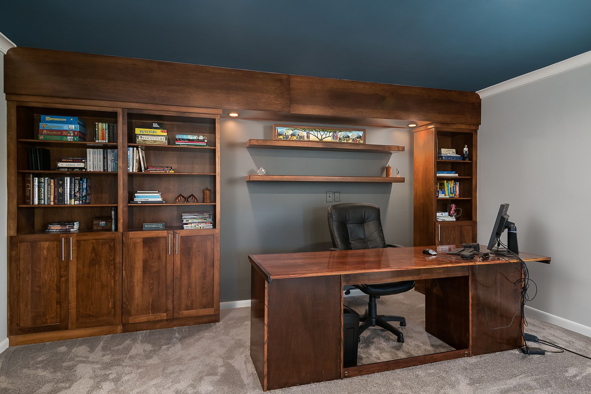 A home office with a desk , chair , shelves and a computer.