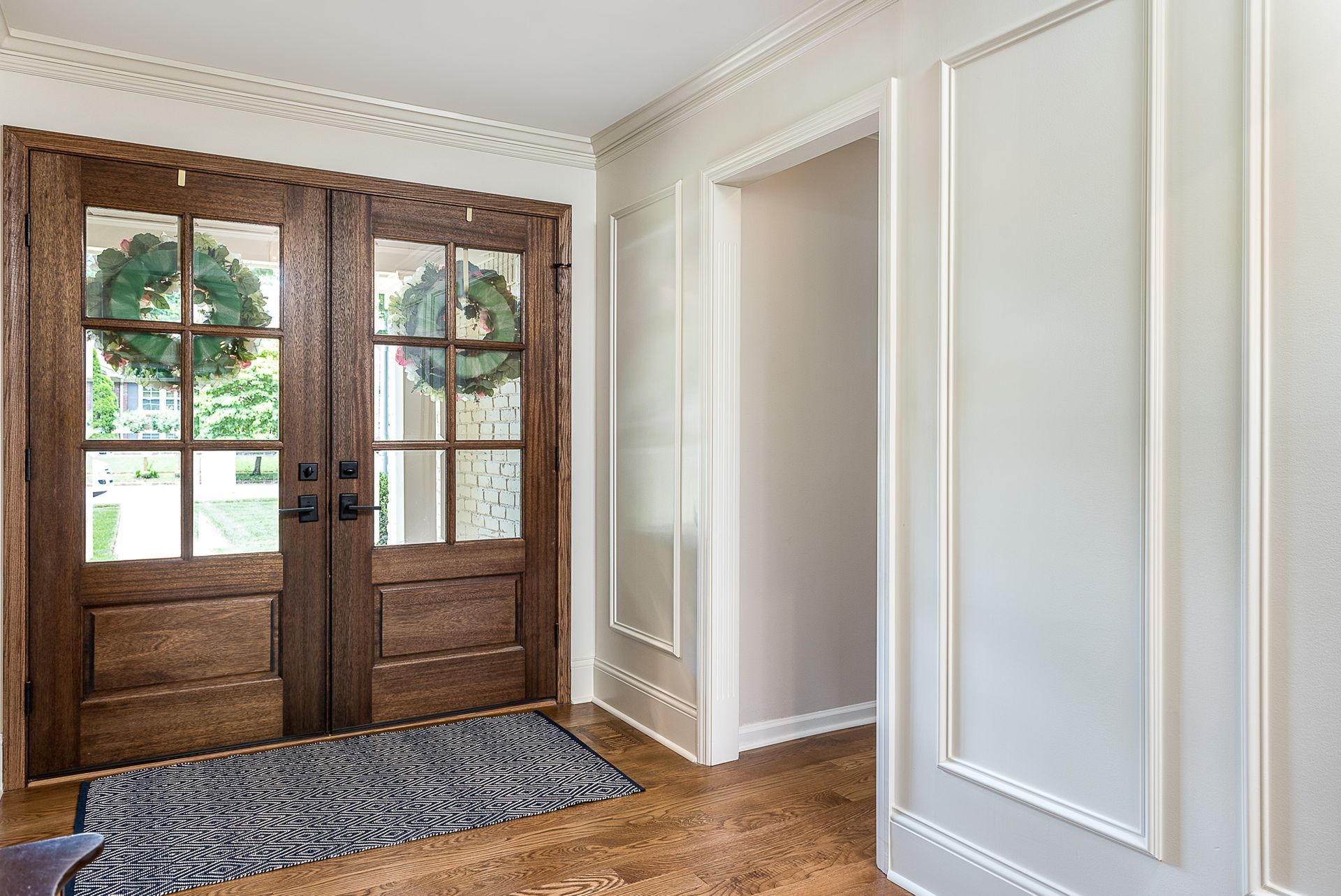 A hallway with two wooden doors and a rug.