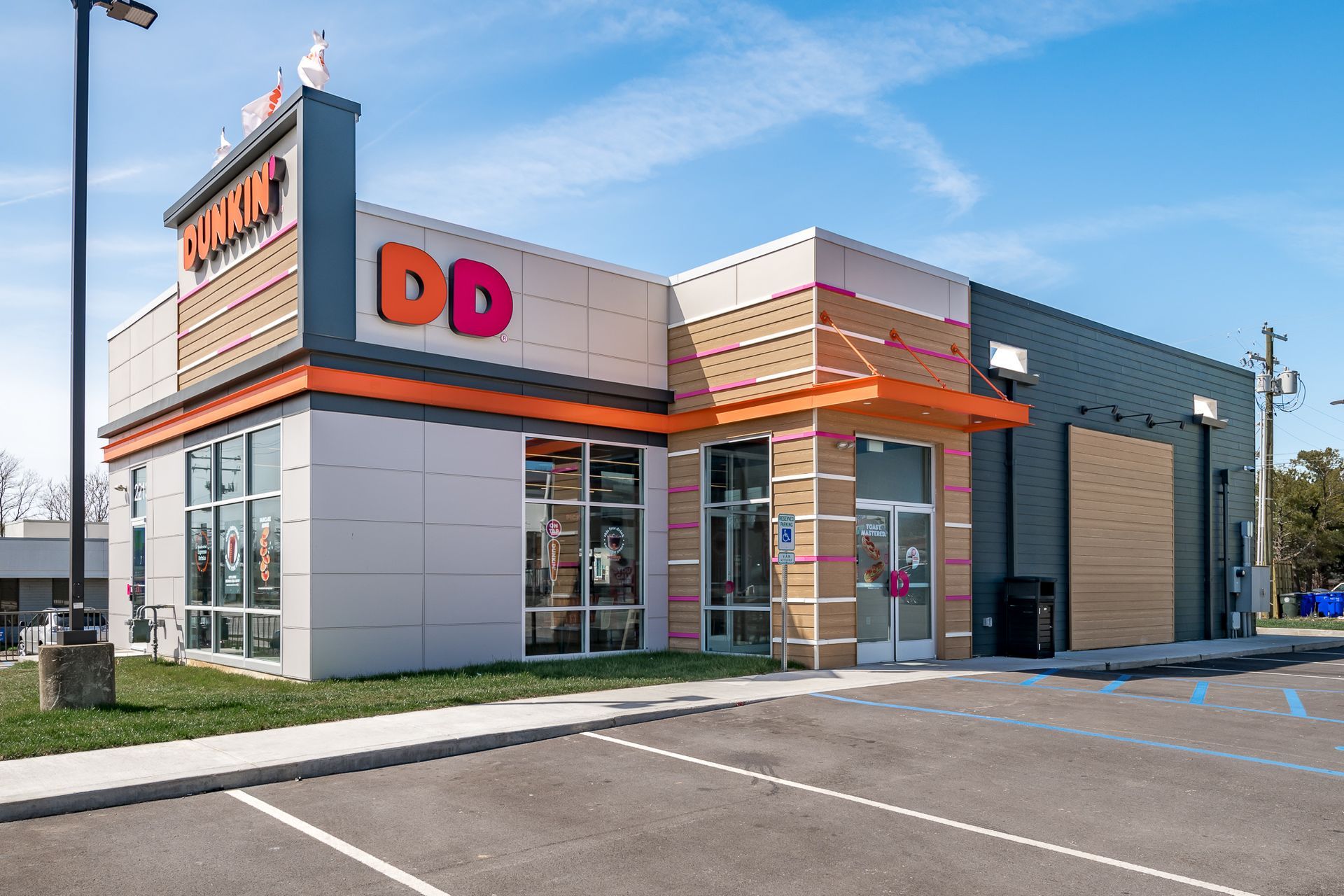 A dunkin donuts restaurant with a parking lot in front of it.