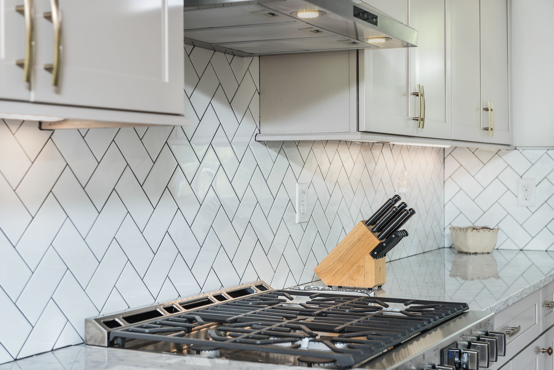 White tile backsplash in kitchen with cabinets and stovetop