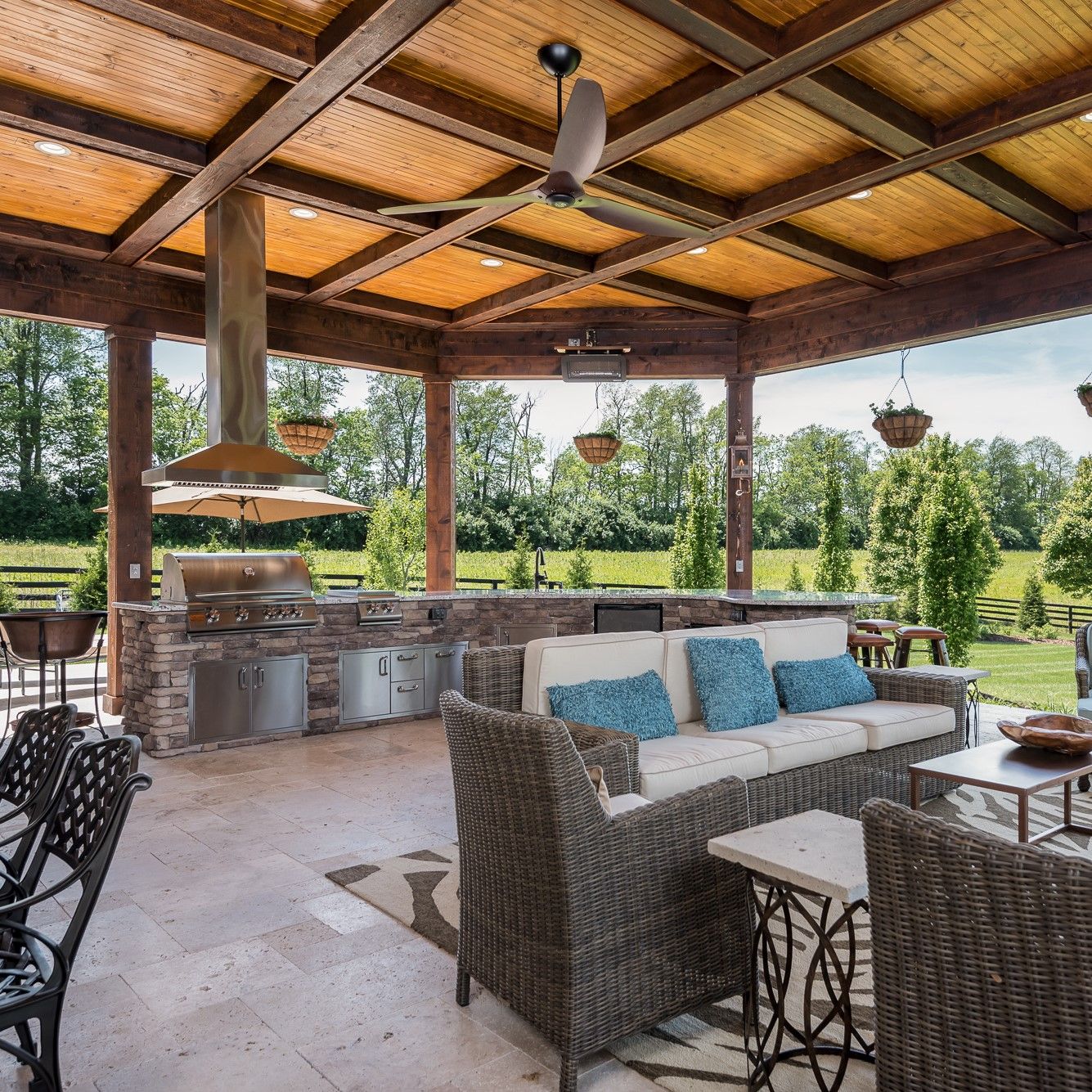 A patio with a couch , chairs , tables and a ceiling fan.