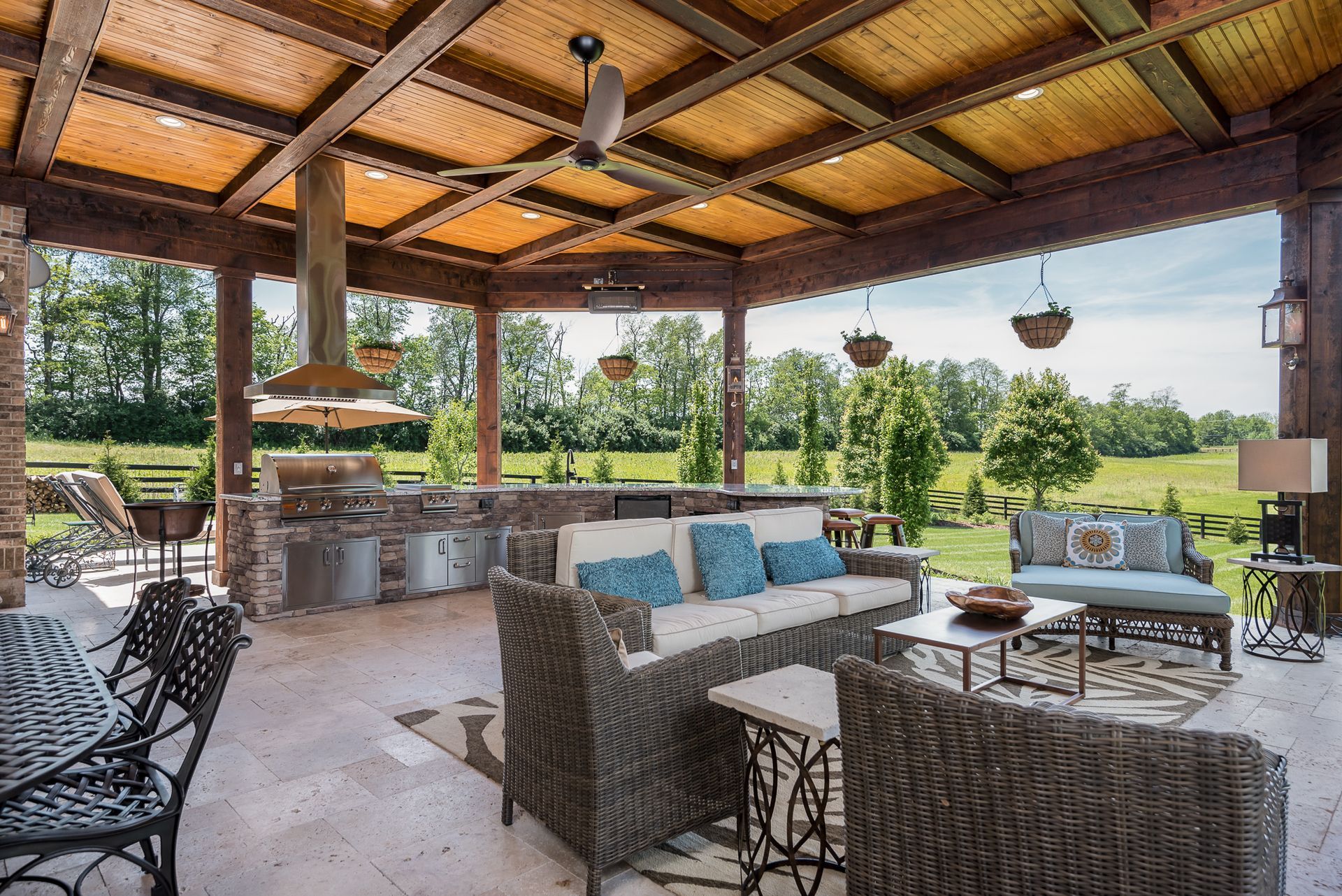A patio with a couch , chairs , tables and a ceiling fan.