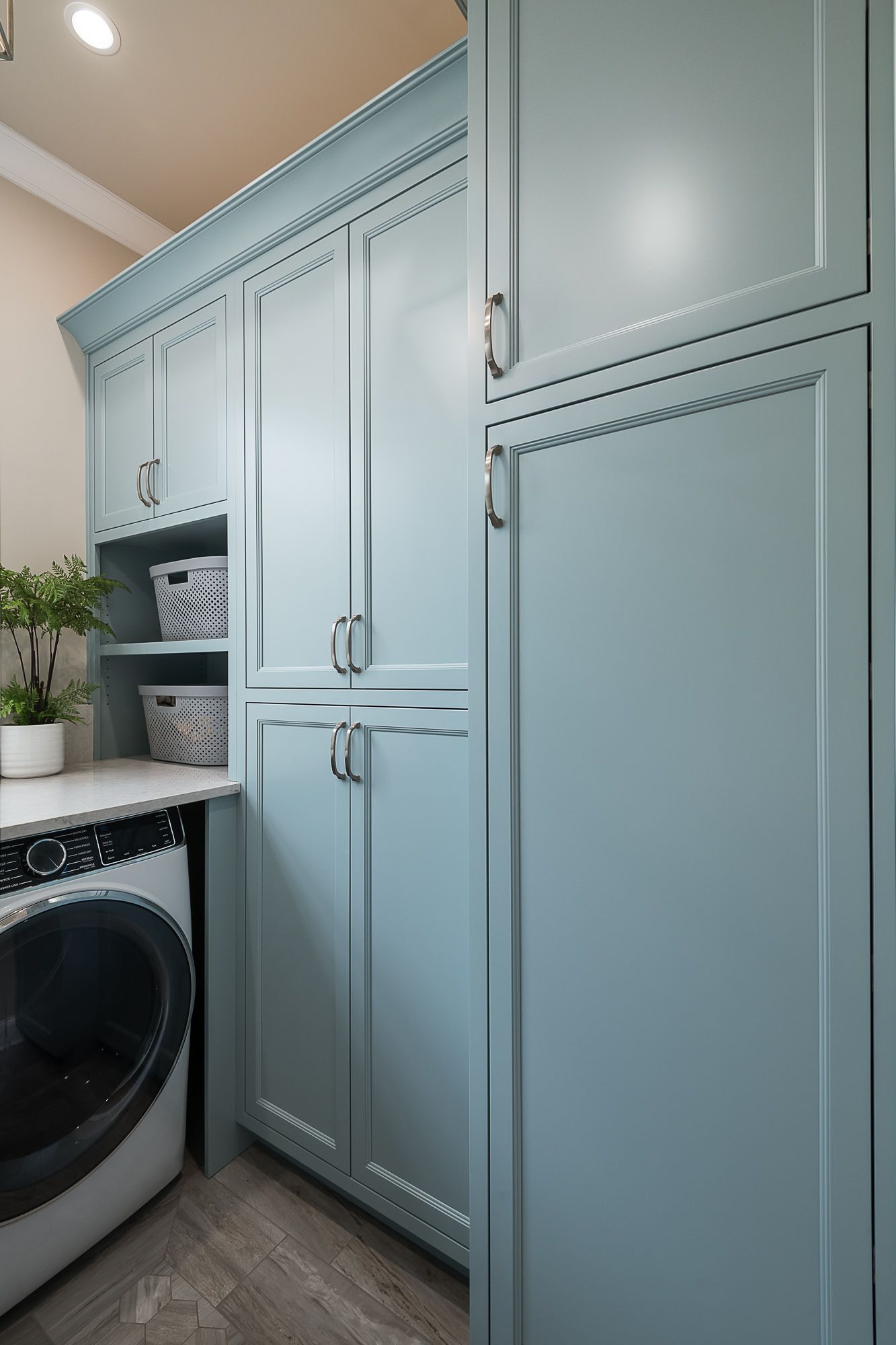 A laundry room with a washer and dryer and blue cabinets.