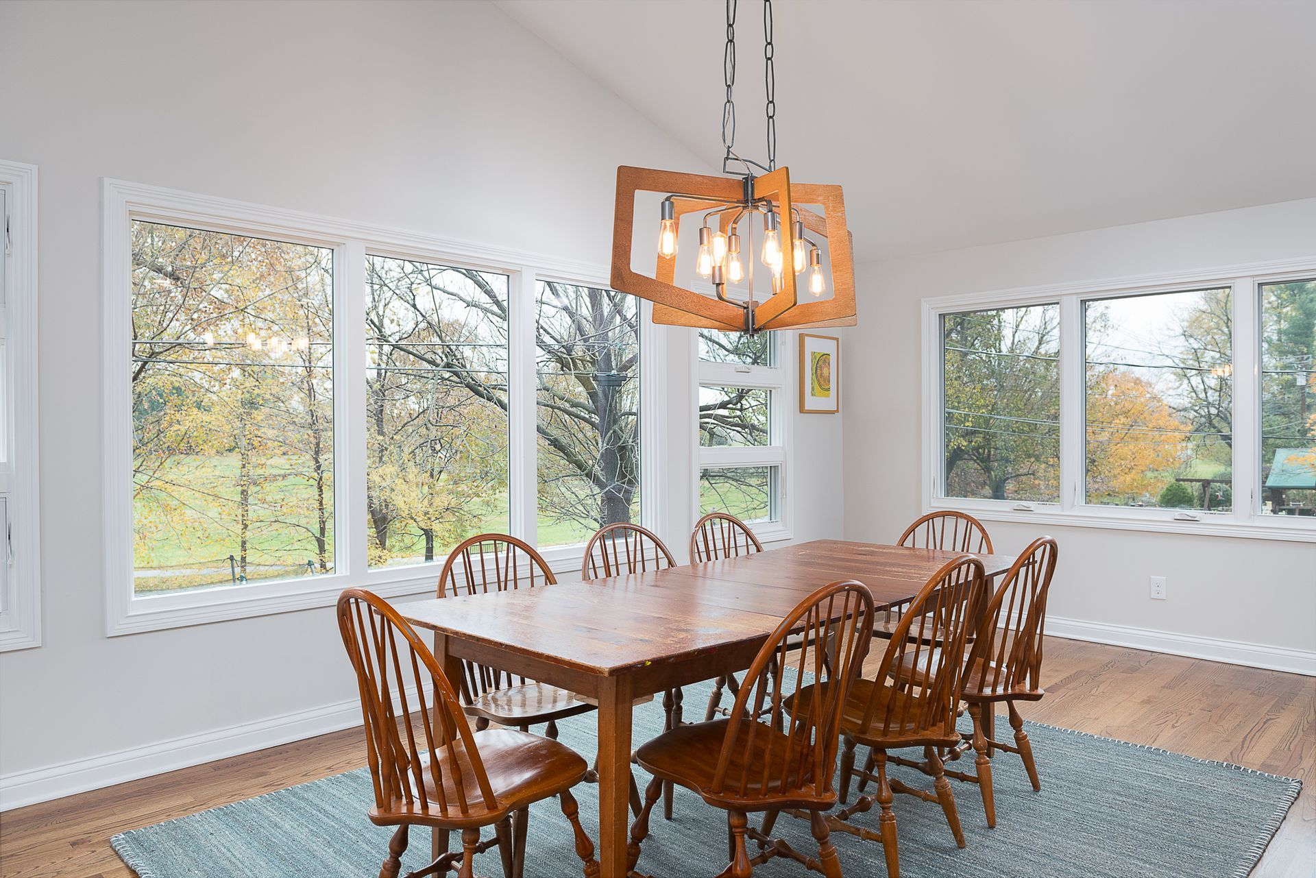 A dining room with a wooden table and chairs and a chandelier.