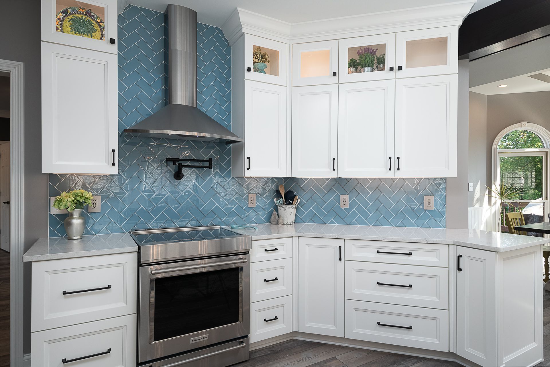 A kitchen with white cabinets , stainless steel appliances , and blue tiles.