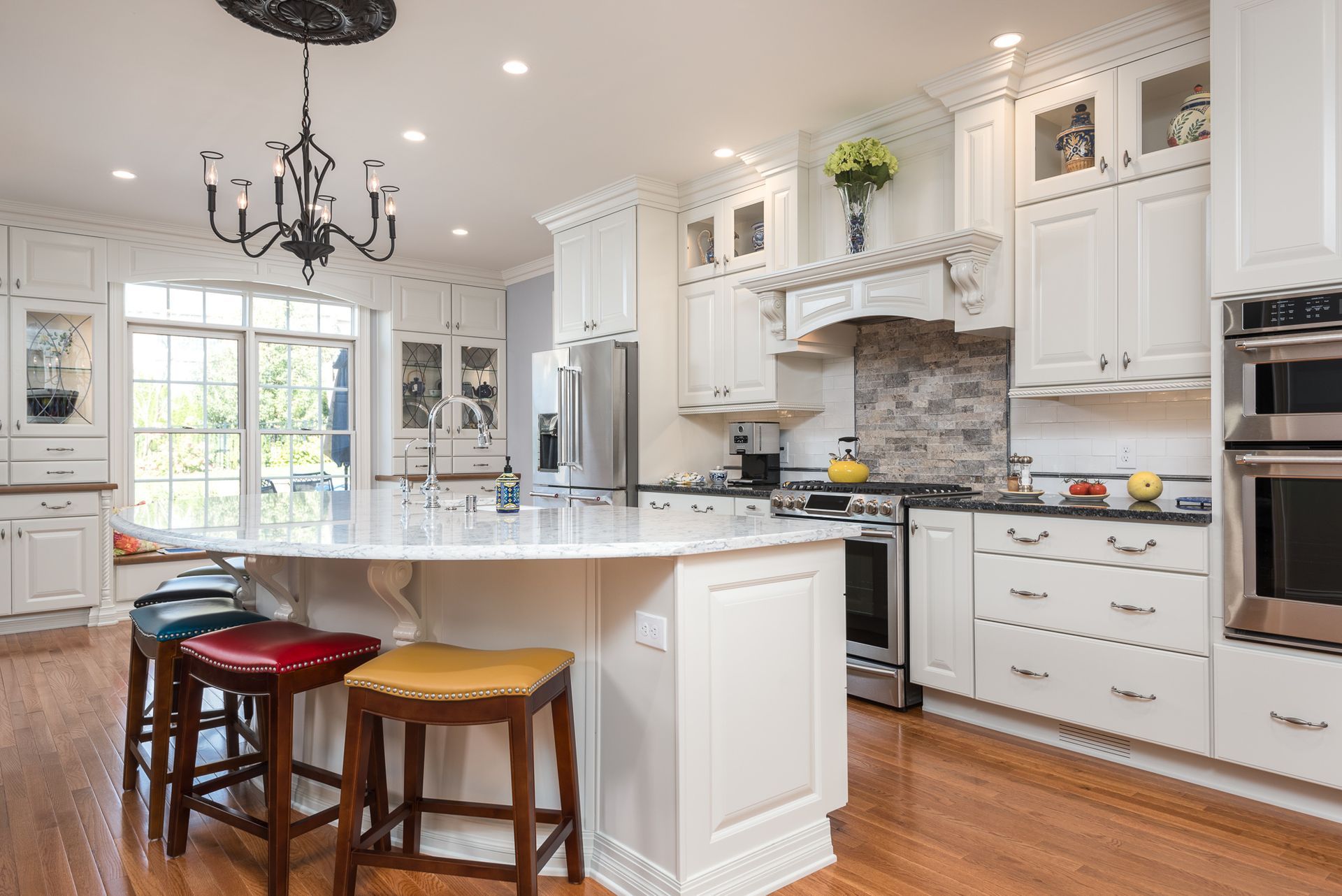 A kitchen with white cabinets and stools and a large island in the middle.
