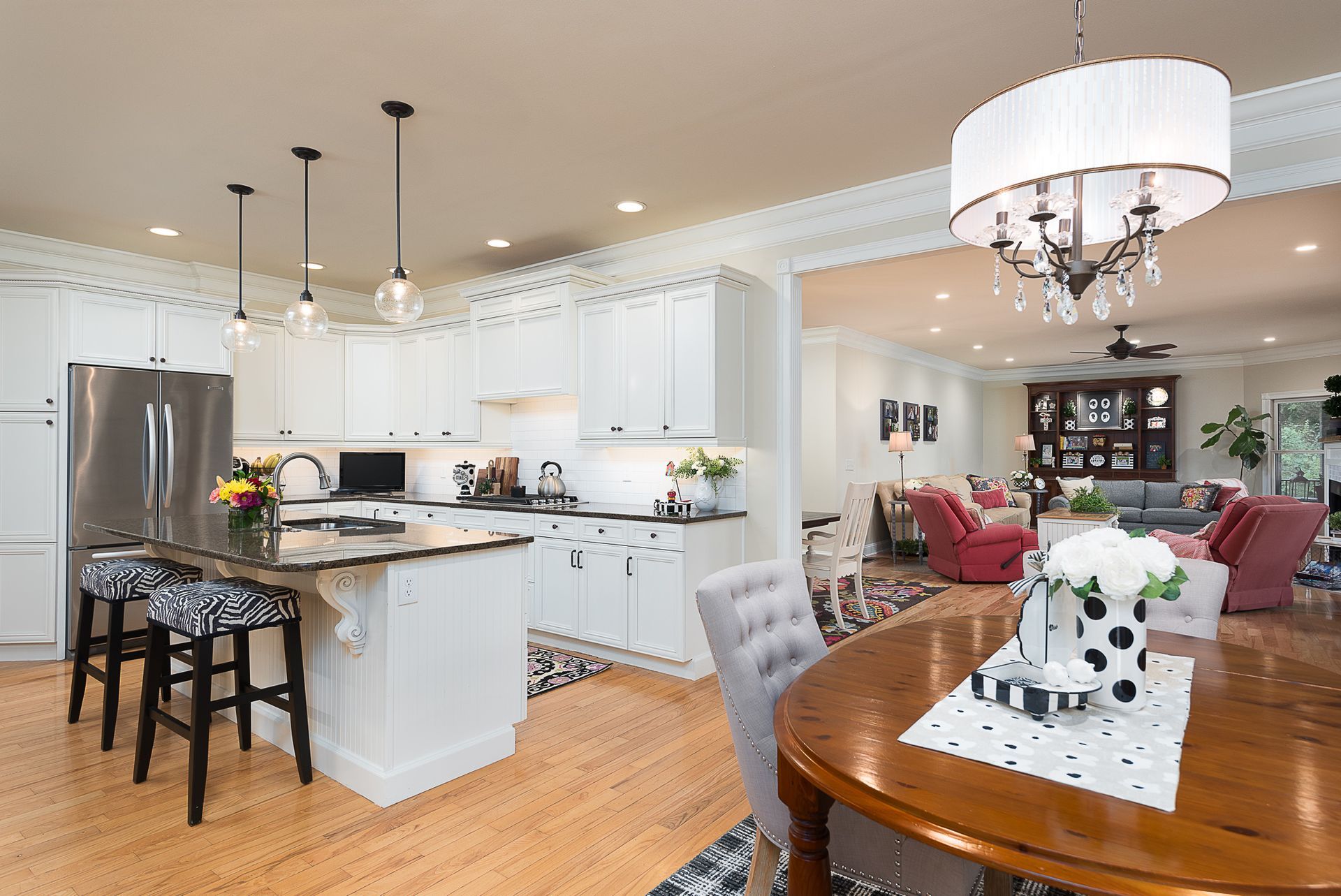 A kitchen with white cabinets , stainless steel appliances , a table and chairs.