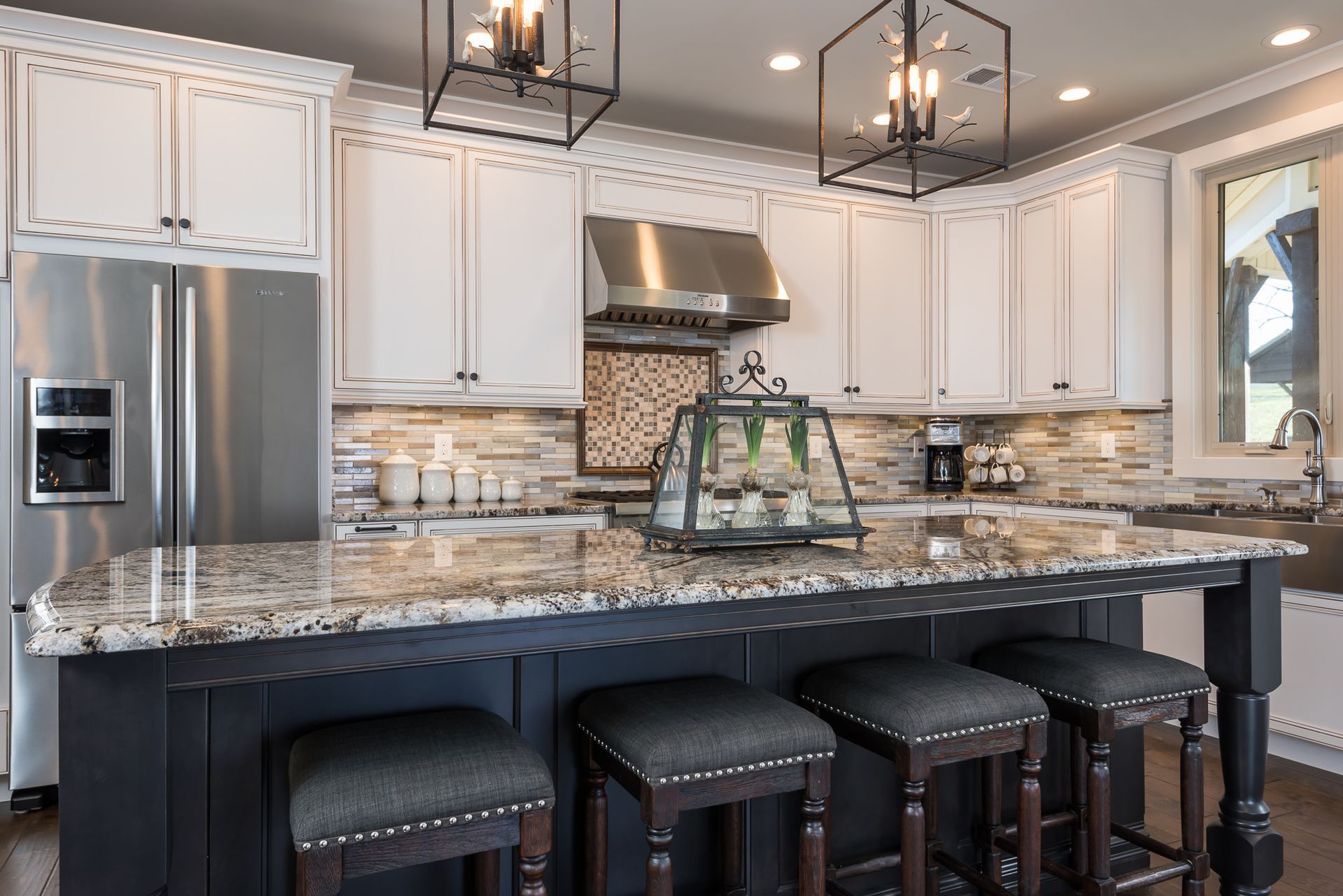 A kitchen with white cabinets , granite counter tops , stainless steel appliances and a large island.