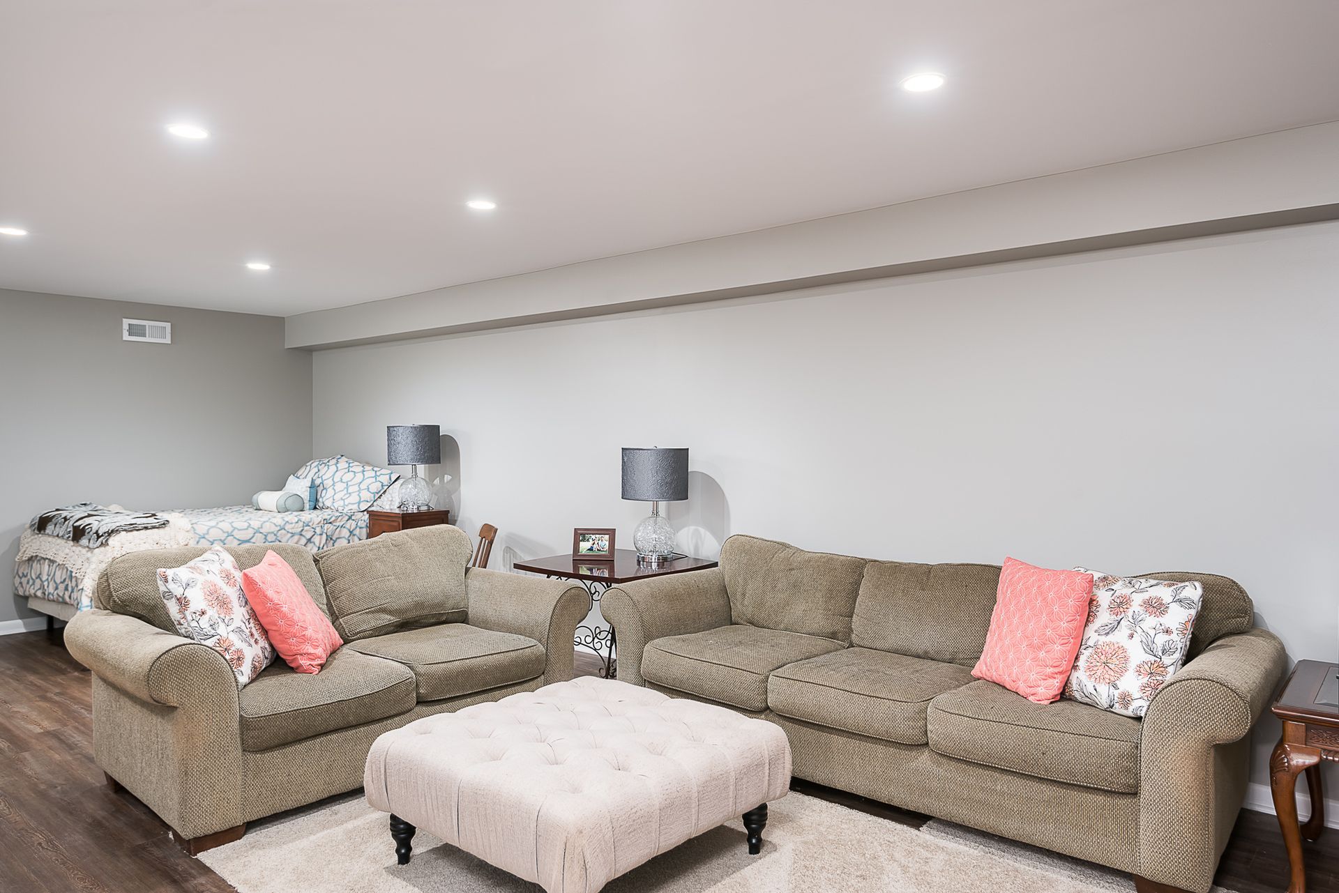 A living room with two couches , an ottoman , and a bed.