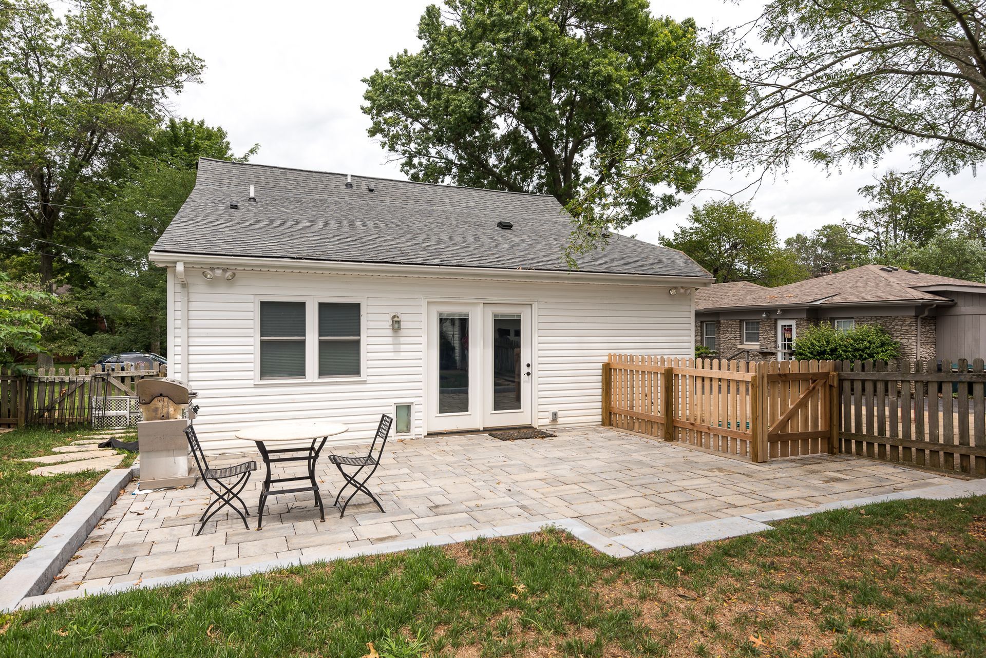A white house with a patio and a table and chairs in front of it.