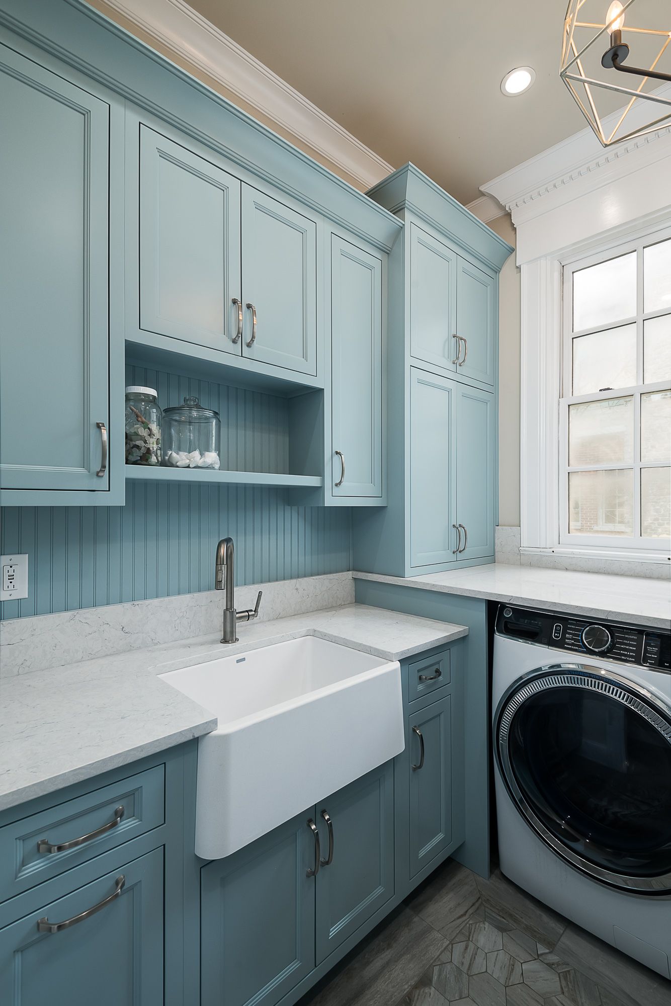 A laundry room with blue cabinets , a washer and dryer , and a sink.