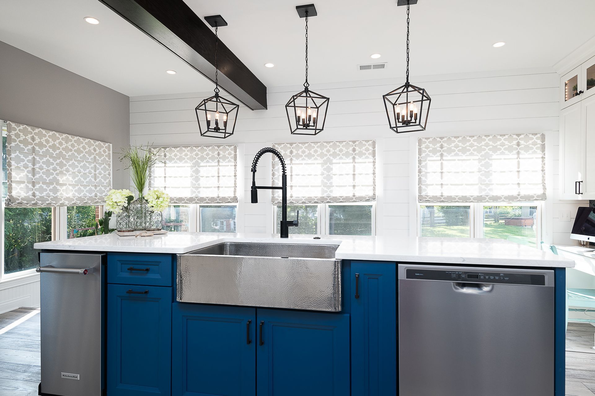 A kitchen with blue cabinets , a stainless steel sink , and a stainless steel dishwasher.