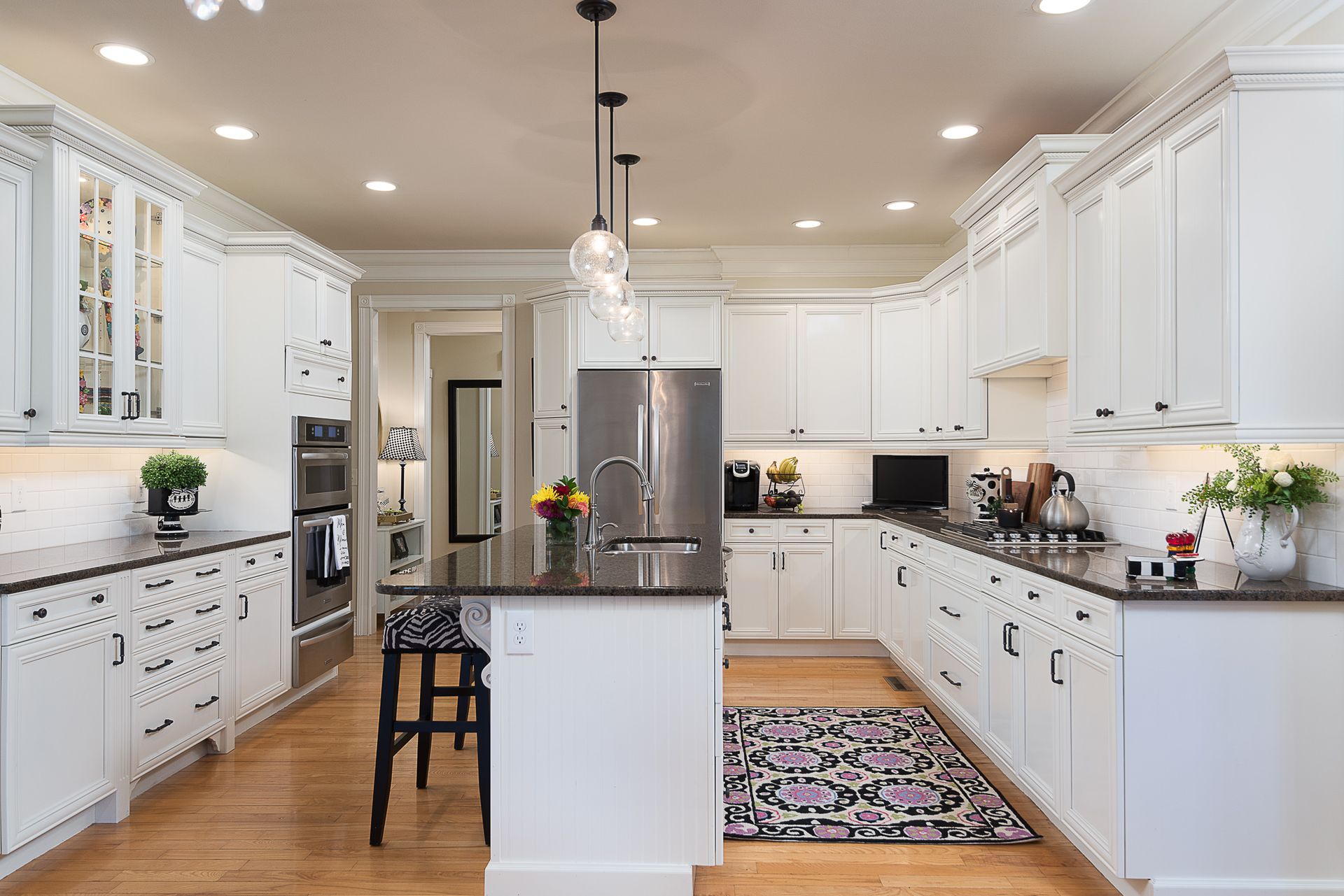 A kitchen with white cabinets , stainless steel appliances , and a large island.