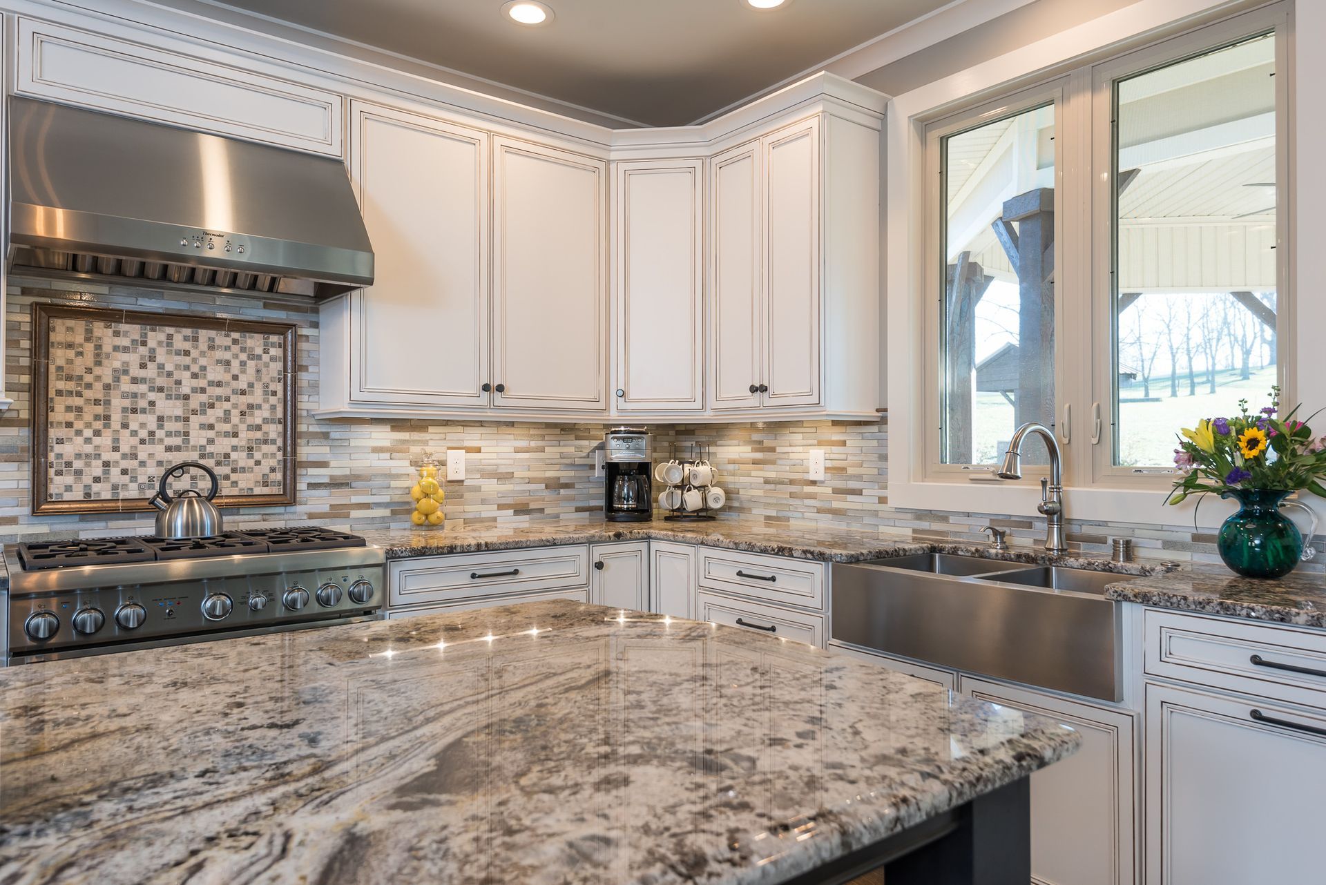 A kitchen with granite counter tops , stainless steel appliances , and white cabinets.