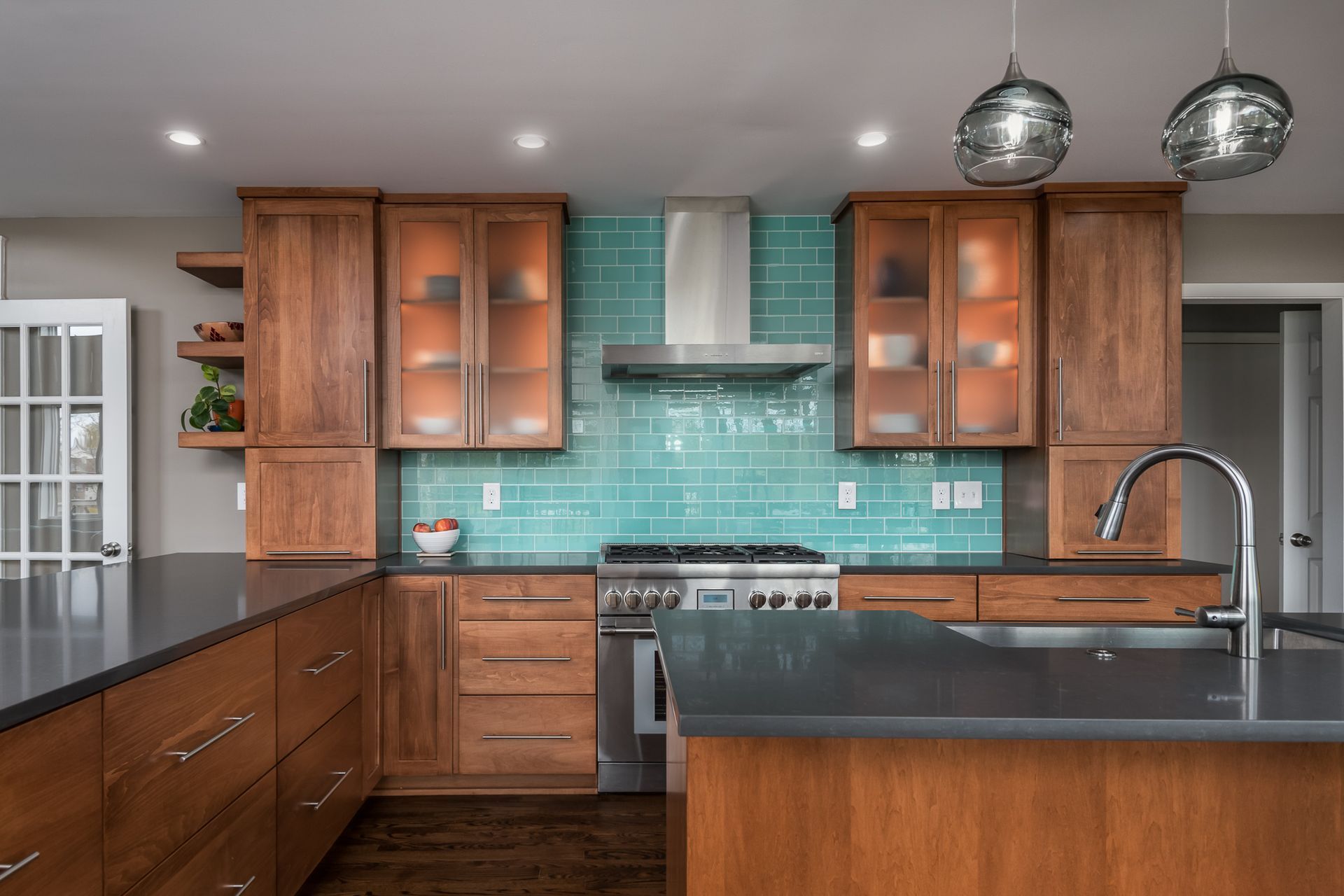 A kitchen with wooden cabinets , a stove , a sink and a hood.