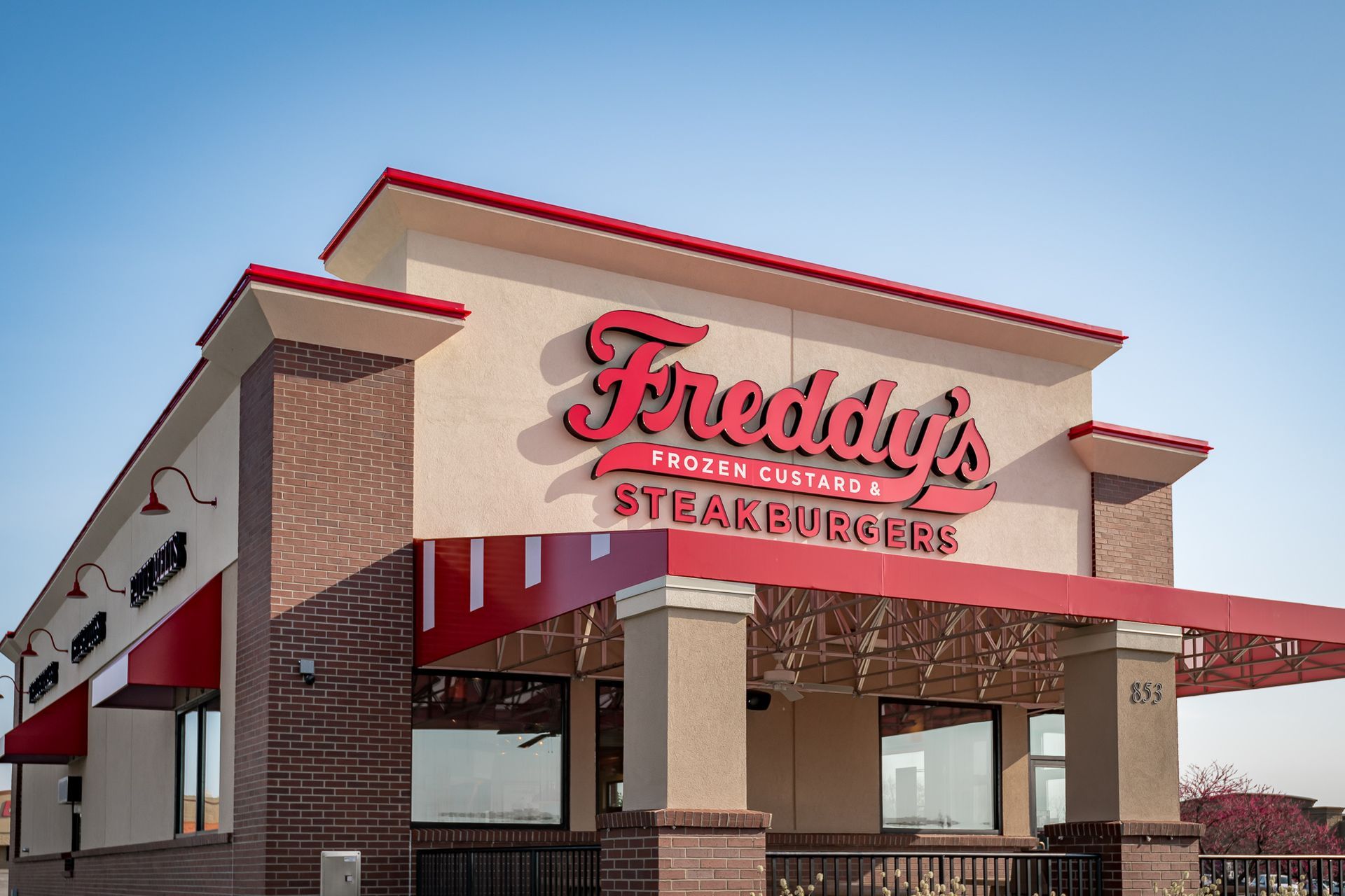 The front of a freddy 's steak and burgers restaurant with a red awning.