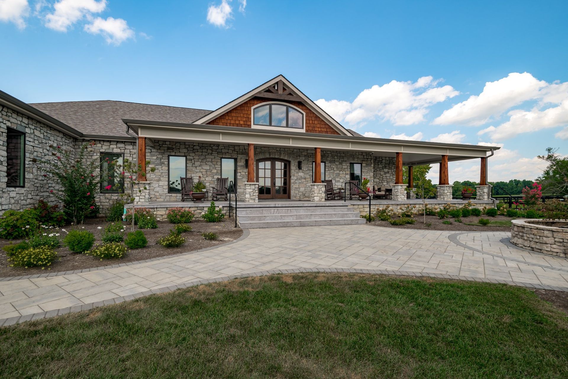 A large stone house with a large porch and a walkway leading to it.