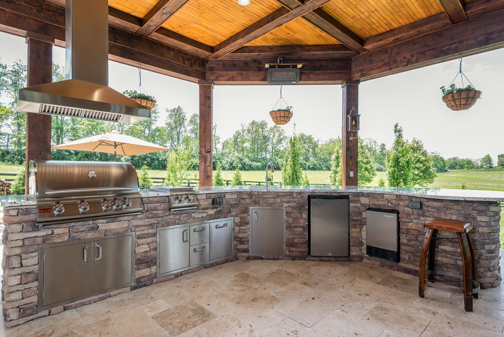 A large outdoor kitchen with stainless steel appliances and a wooden ceiling.