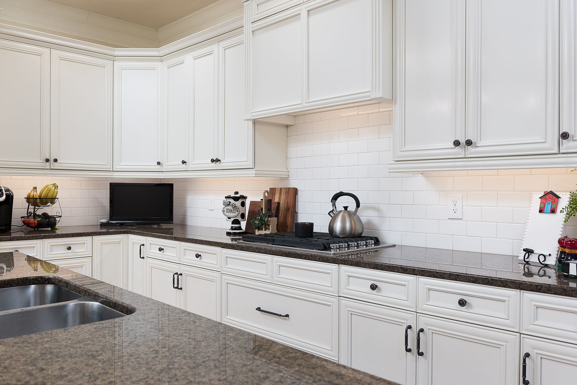 A kitchen with white cabinets and granite counter tops.