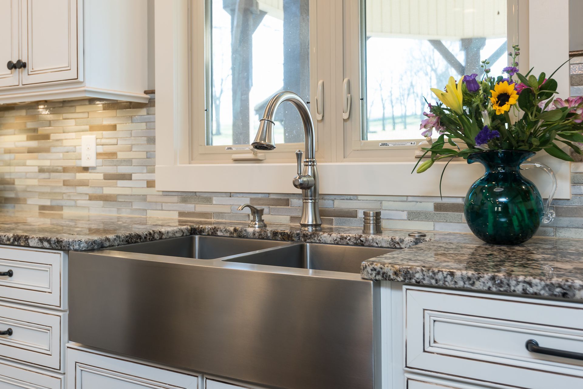 A kitchen sink with a vase of flowers on the counter.
