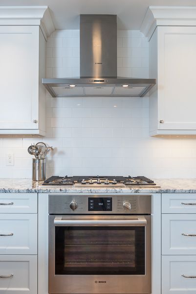 A kitchen with white cabinets and a stainless steel oven