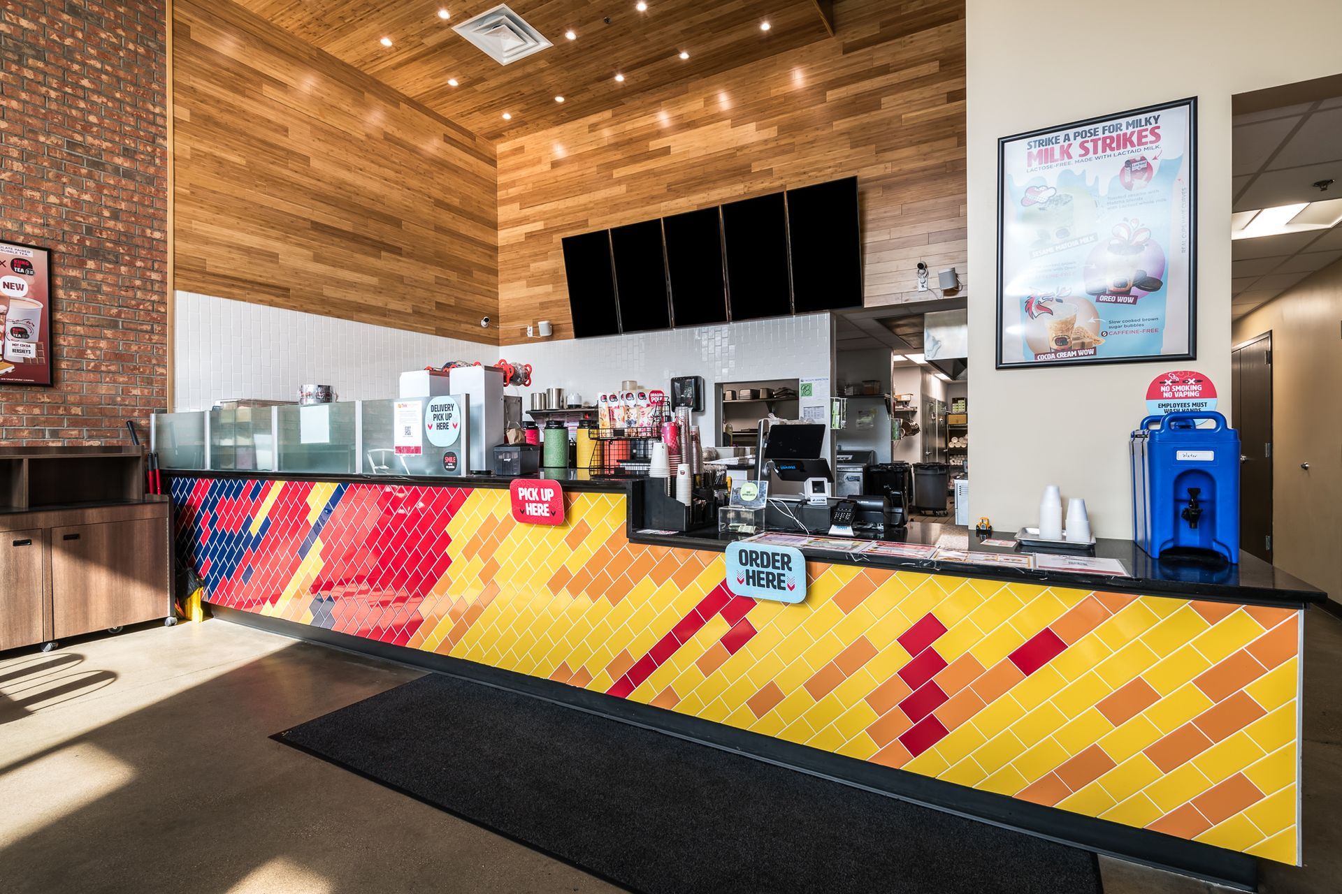 A restaurant with a colorful counter and a brick wall.