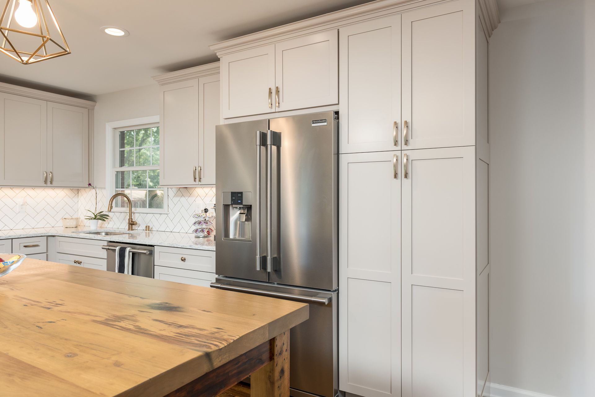 A kitchen with white cabinets and a stainless steel refrigerator.
