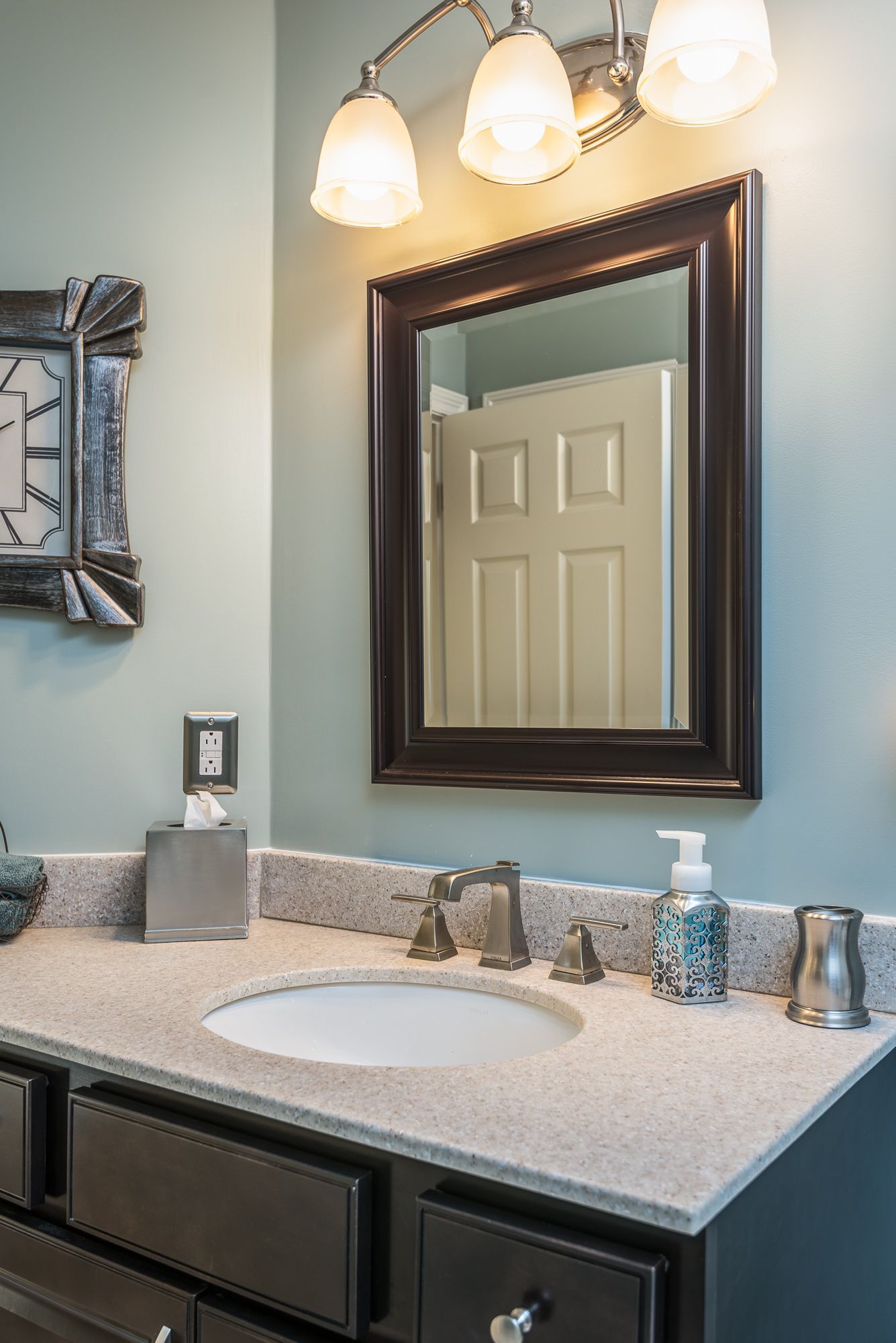 A bathroom with a sink , mirror and clock on the wall.