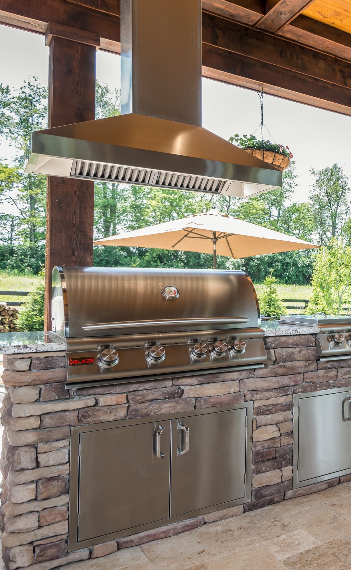 An outdoor kitchen with a grill and umbrellas.