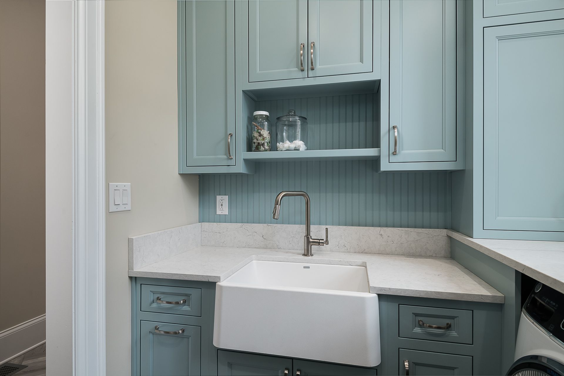 A laundry room with blue cabinets and a white sink.