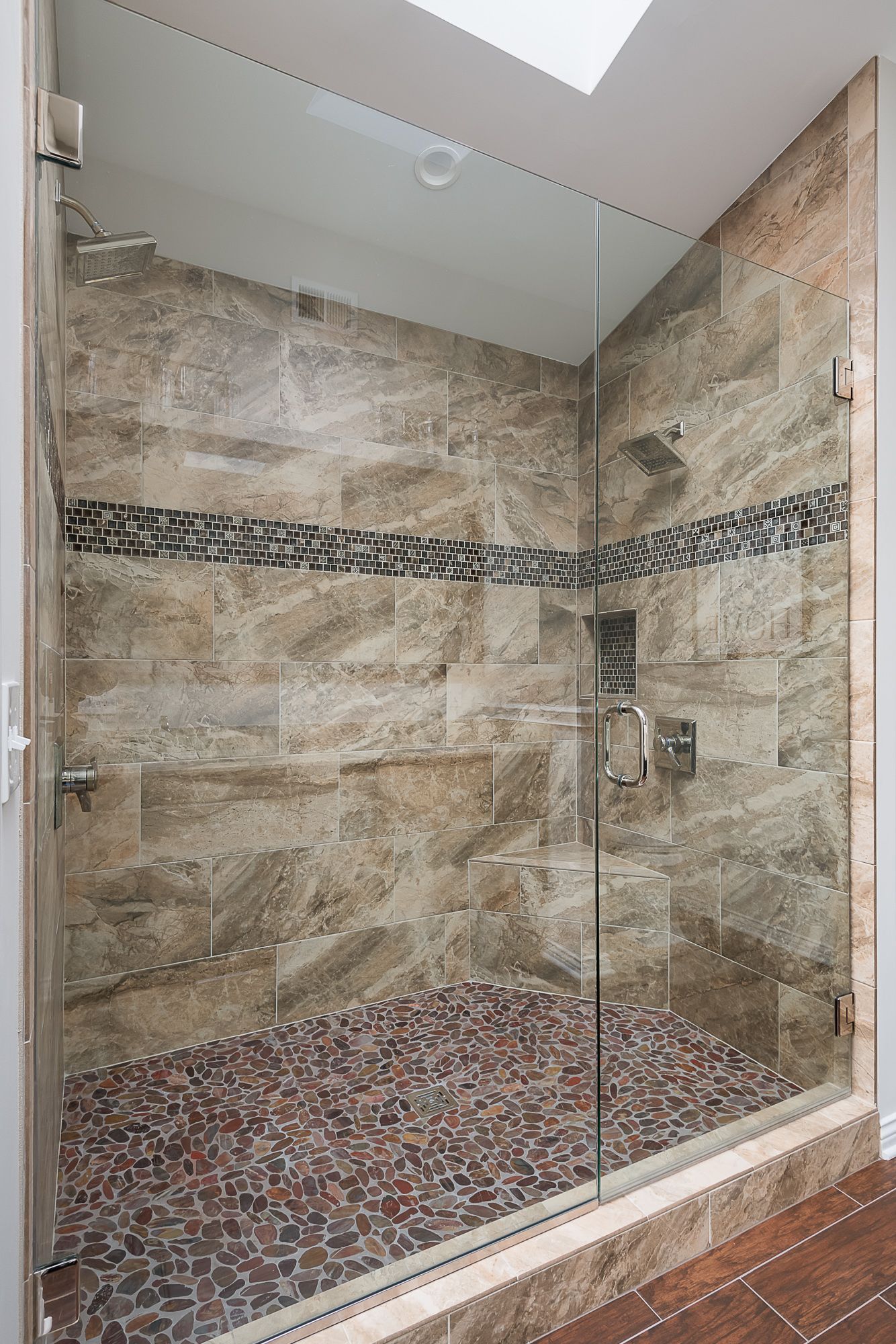 A walk in shower with a glass door and a tiled floor.