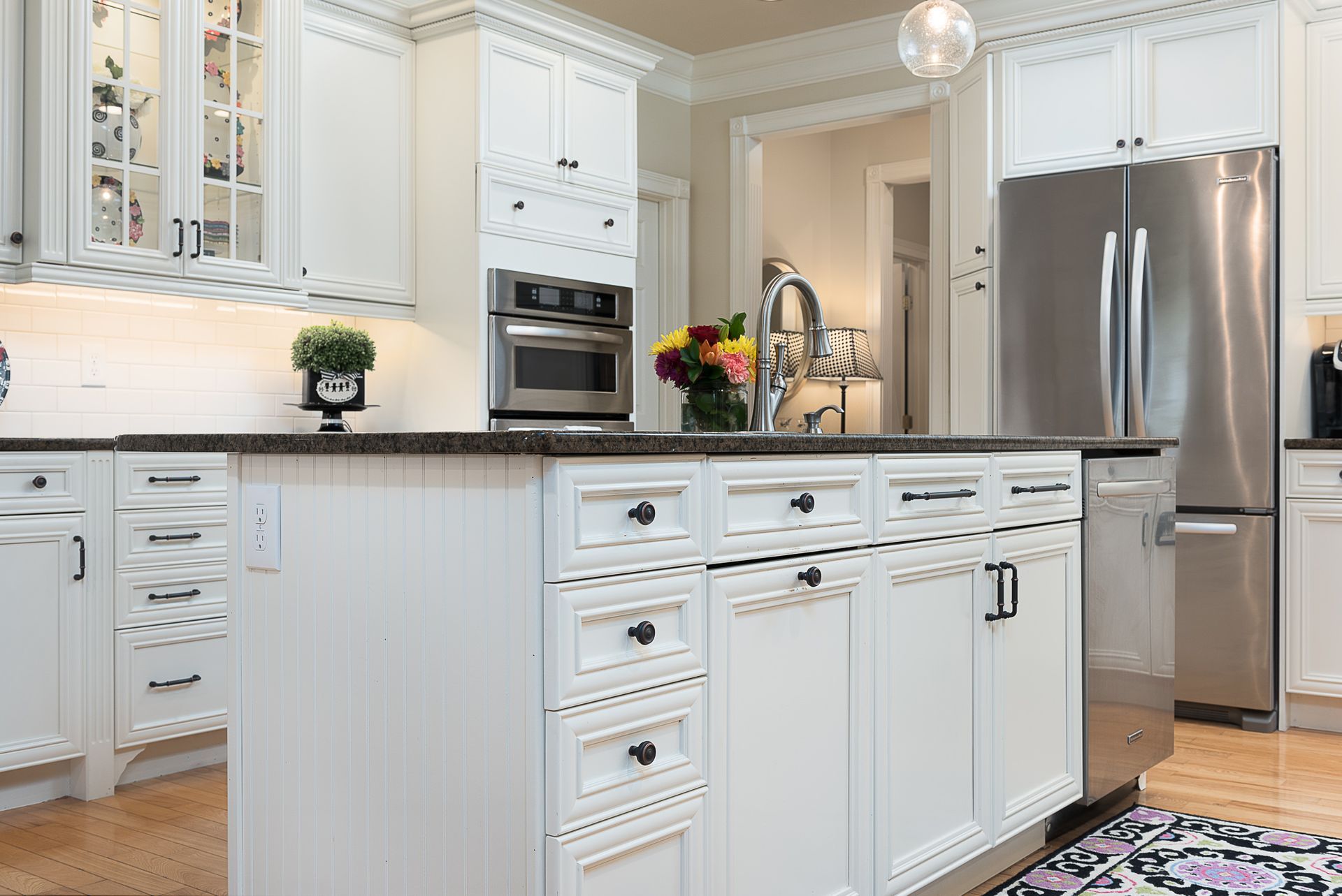 A kitchen with white cabinets , stainless steel appliances , and a large island.