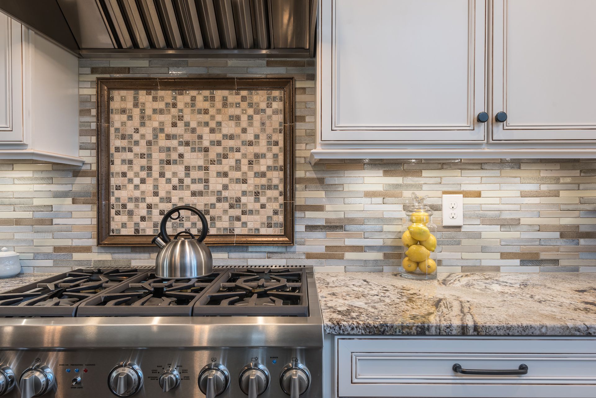 A kitchen with a stove and a kettle on it.