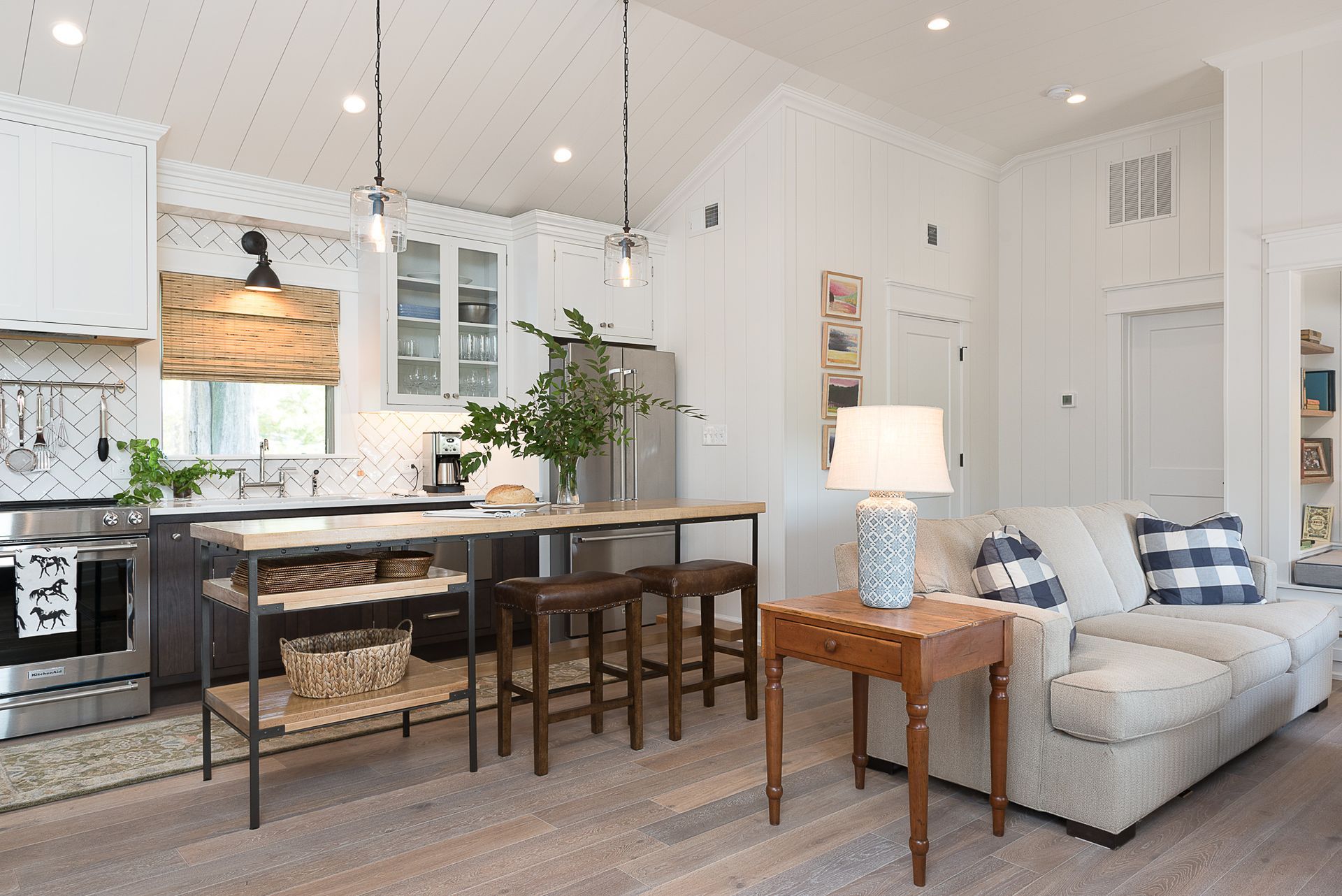 A living room with a couch , table , lamp and kitchen.
