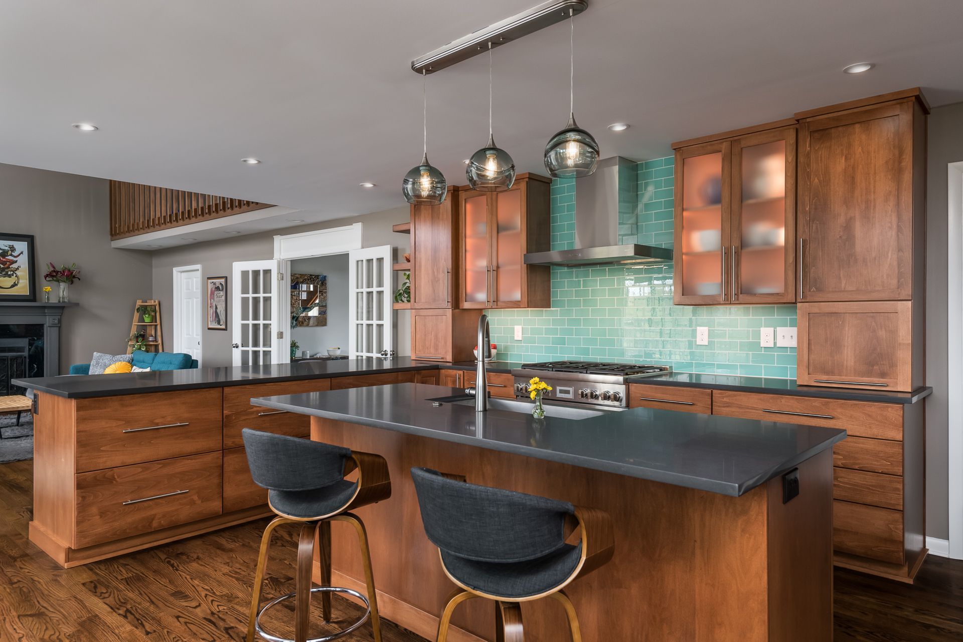 A kitchen with wooden cabinets , granite counter tops , stools and a large island.