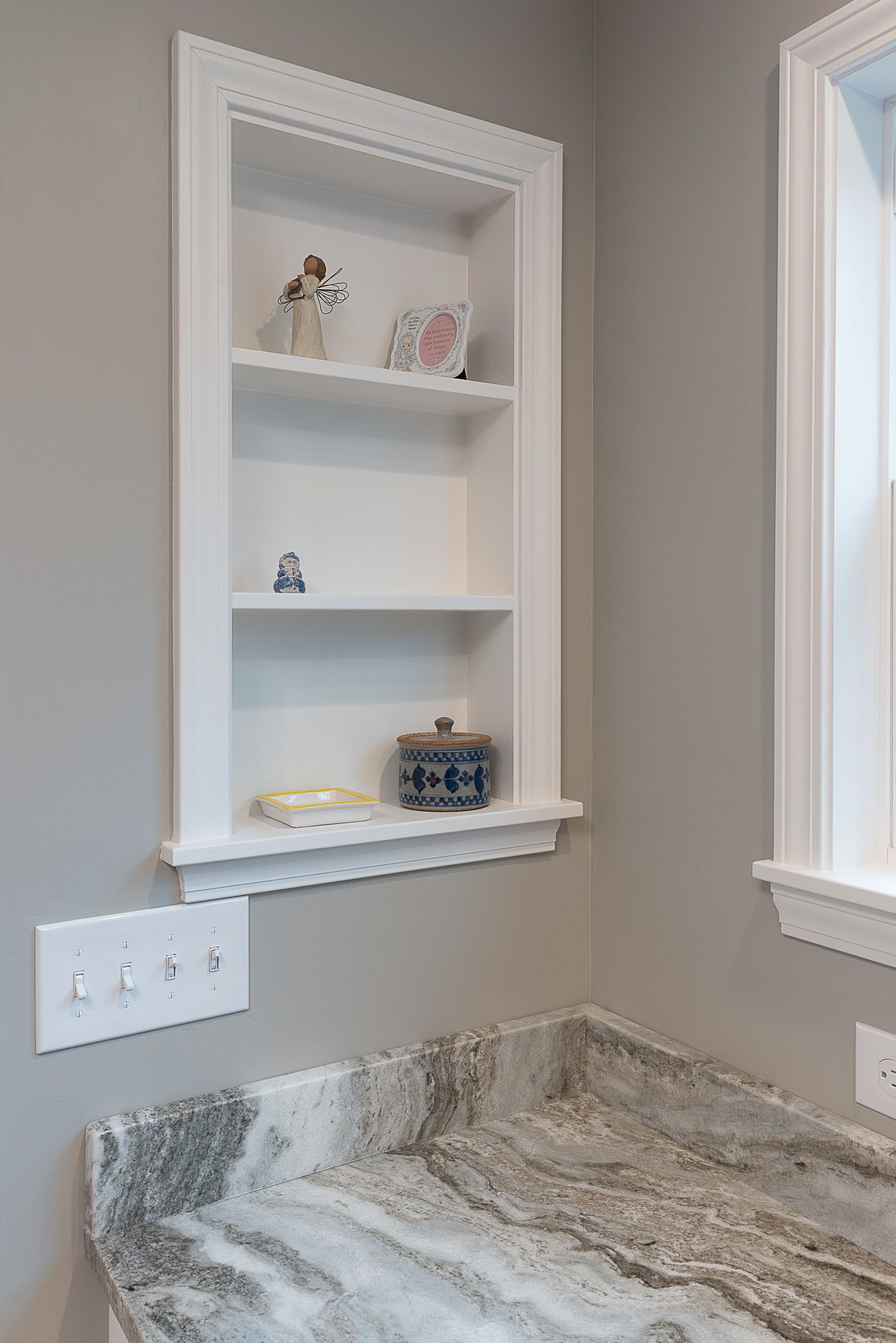 There is a shelf in the wall above the sink in the bathroom.