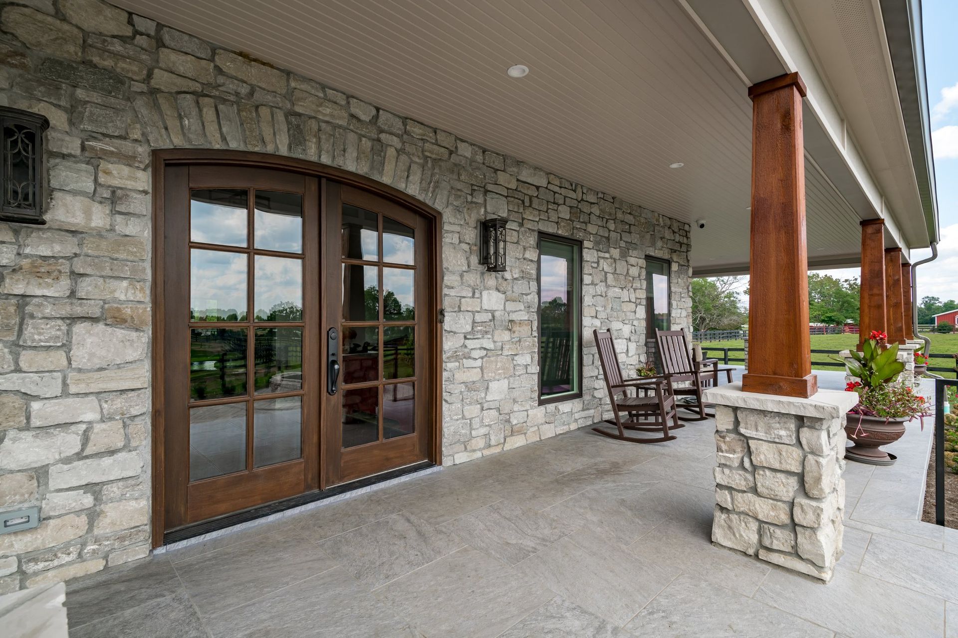 A stone house with a porch and rocking chairs on it.
