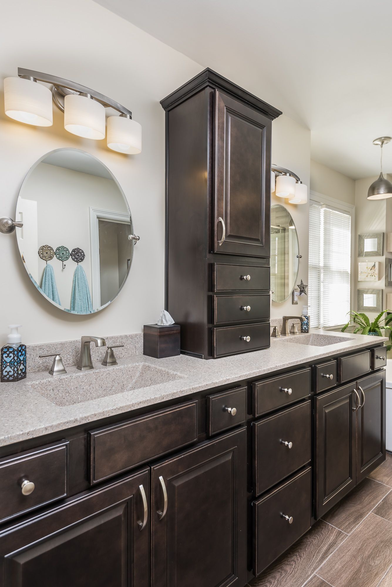 A bathroom with a sink , mirror , cabinets and drawers.