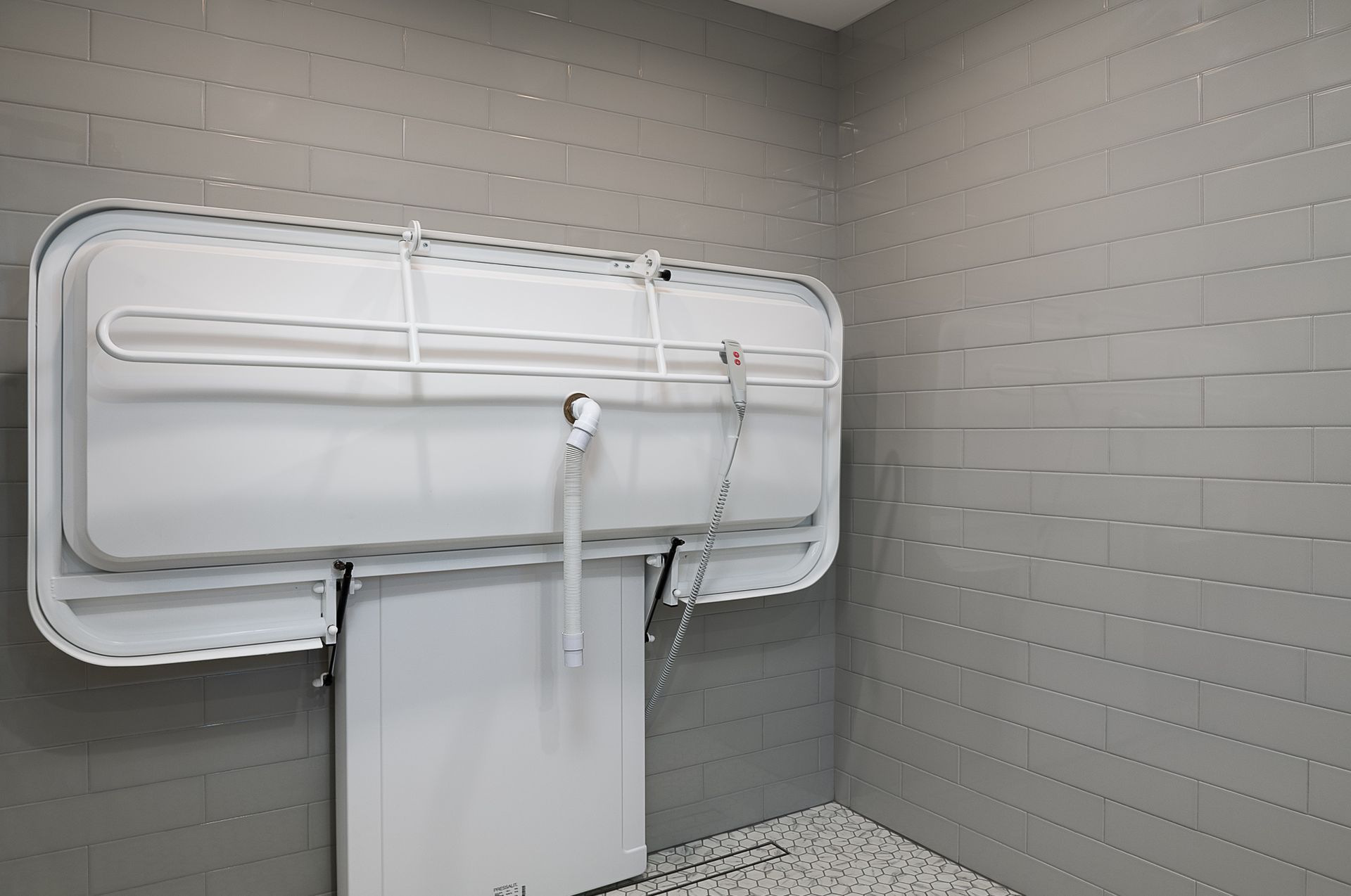 A bathroom with a changing table attached to the wall.