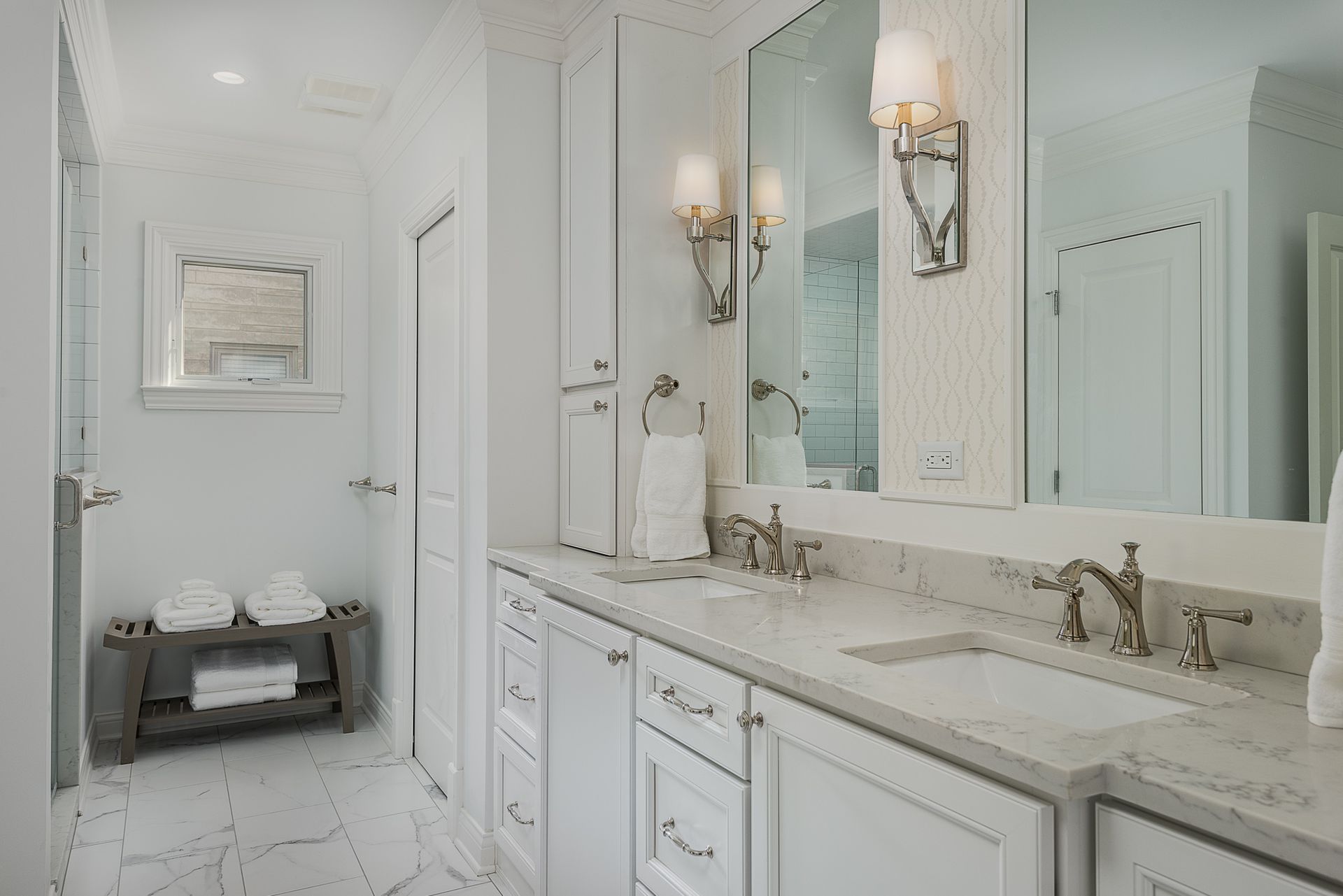 A bathroom with two sinks , two mirrors and a bench.