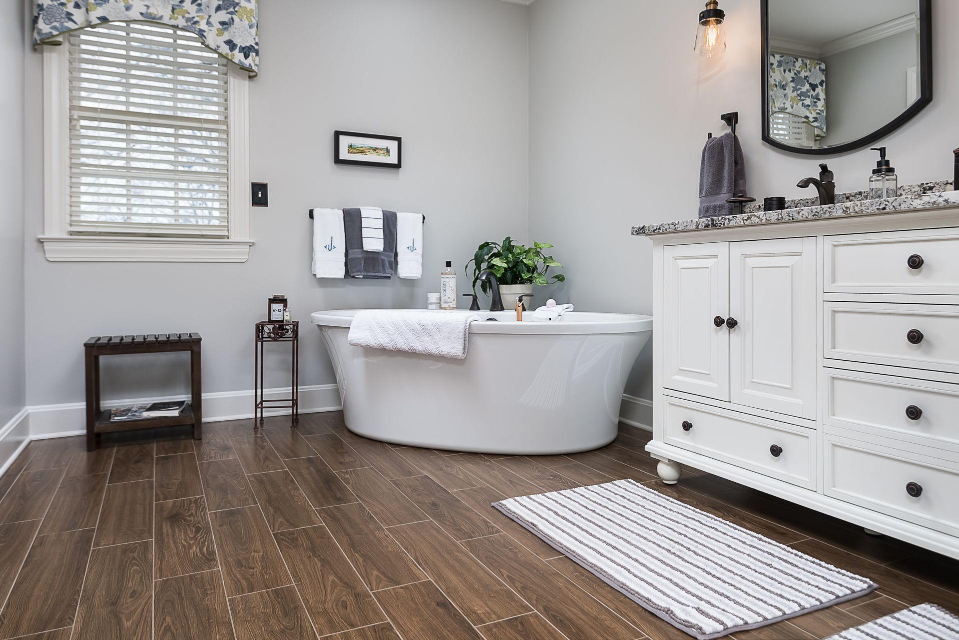 A bathroom with a tub , sink , and mirror.