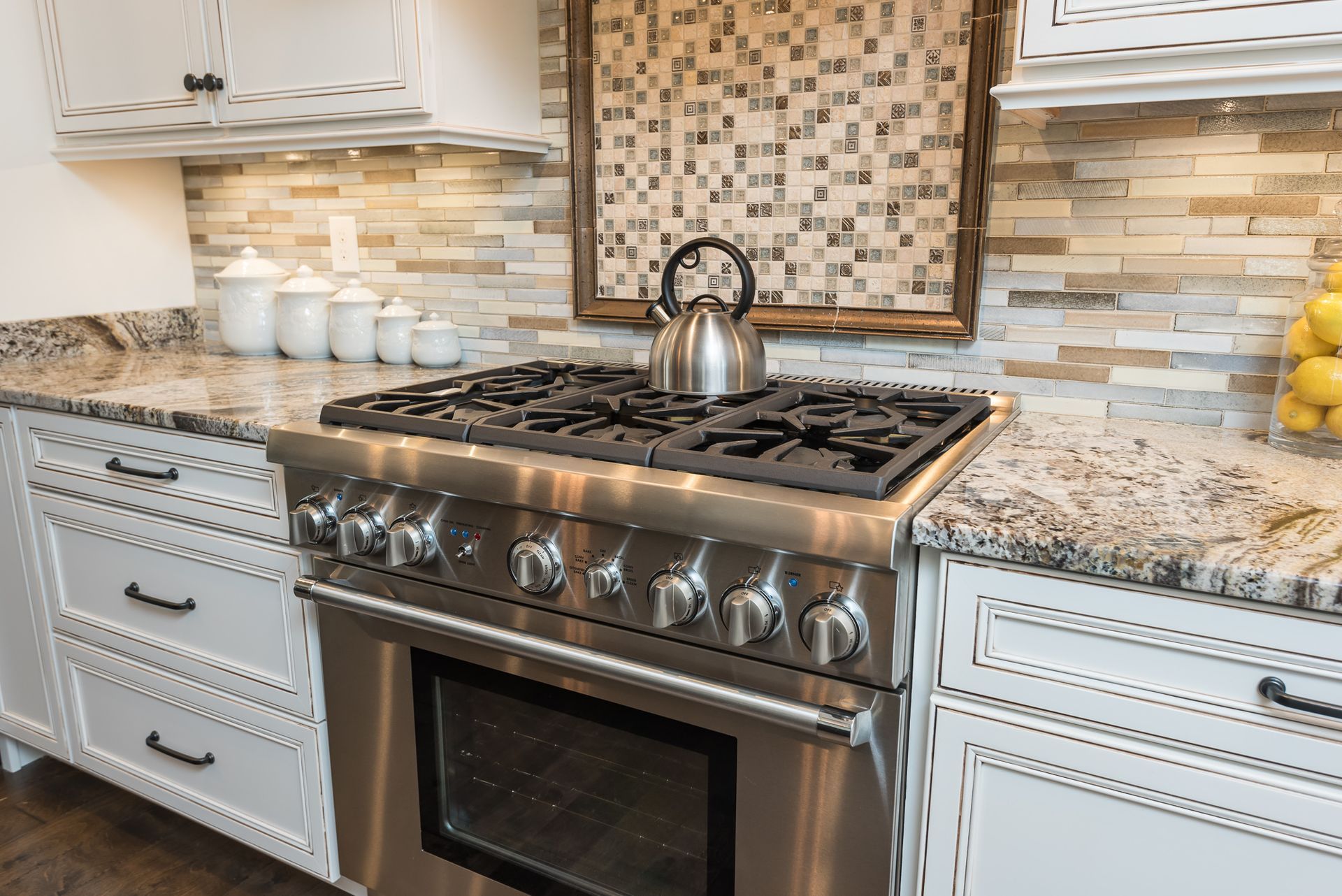 A stainless steel stove with a tea kettle on top of it in a kitchen.