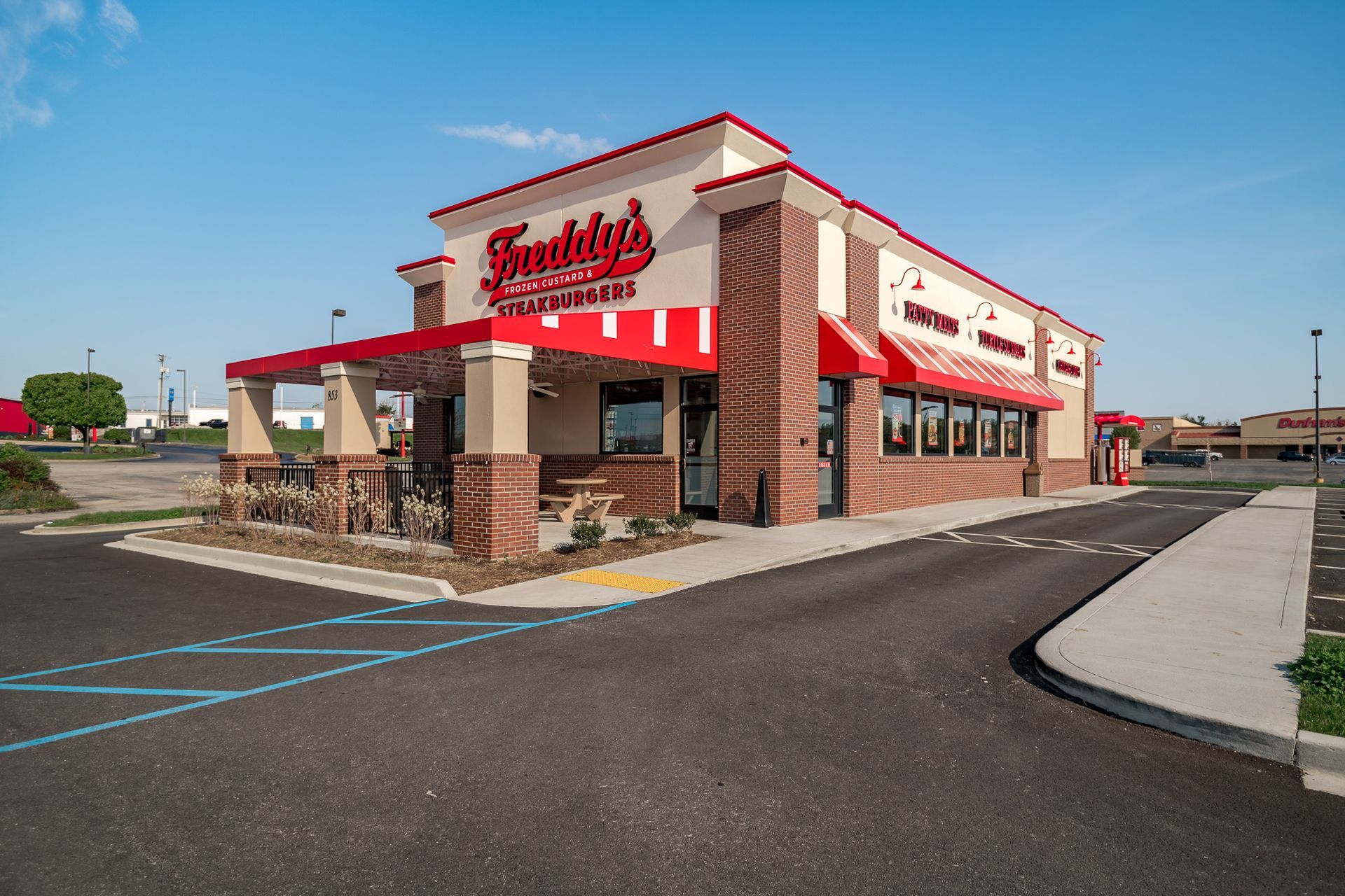 A fast food restaurant with a red awning and a parking lot in front of it