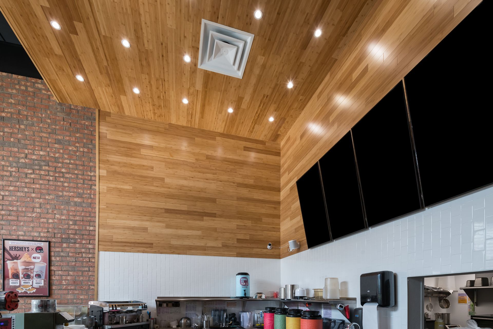 A kitchen with a wooden ceiling and a brick wall.